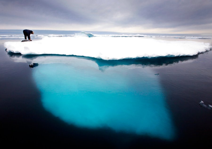 In this file photo dated July 2007, an Inuit seal hunter touches a dead seal atop a melting iceberg near Ammassalik Island, Greenland. (AP Photo/John McConnico, FILE)