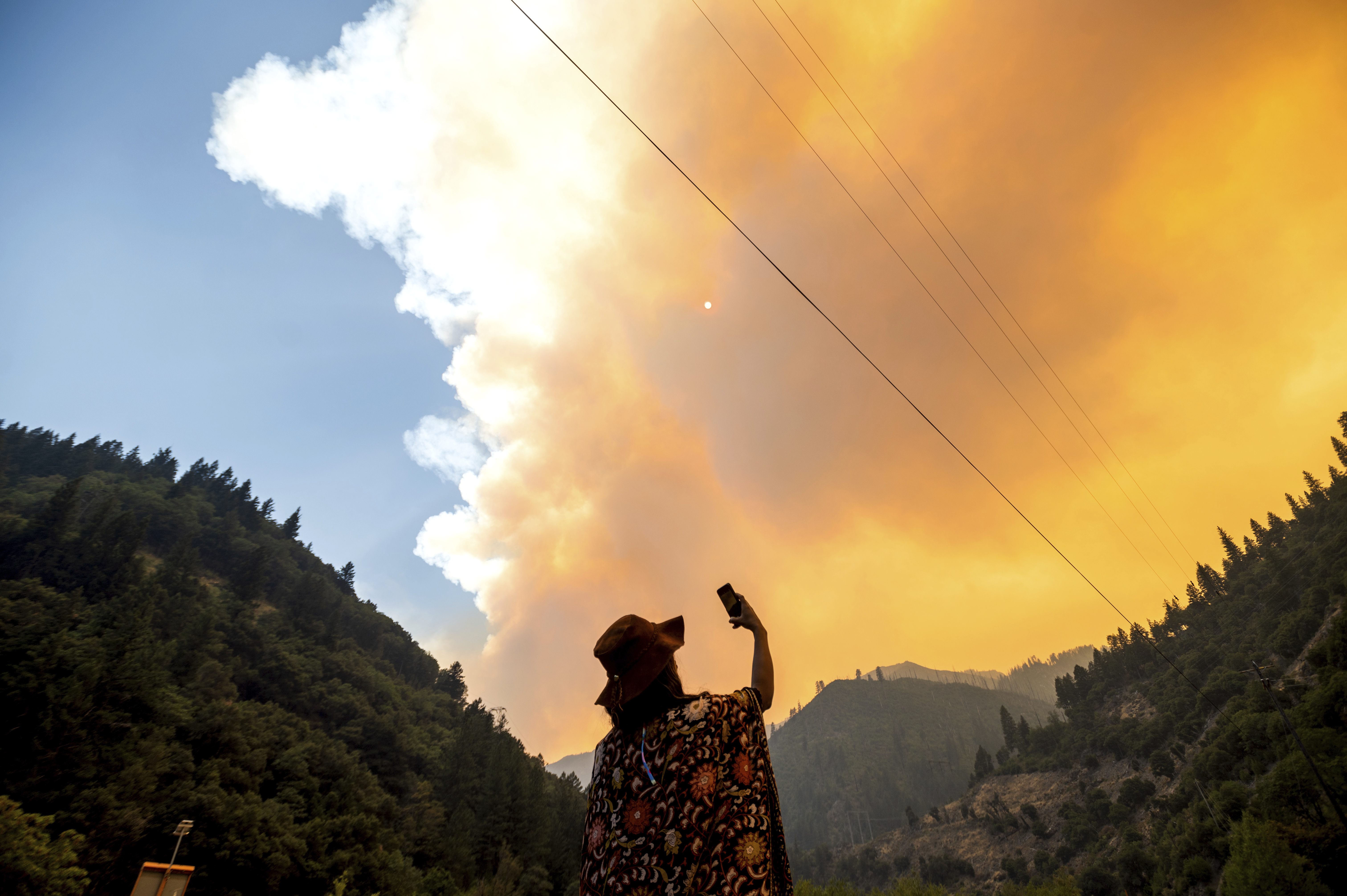 Jessica Bell takes a video as the Dixie Fire burns along Highway 70 in Plumas National Forest, Calif., on July 16, 2021. (AP Photo/Noah Berger)