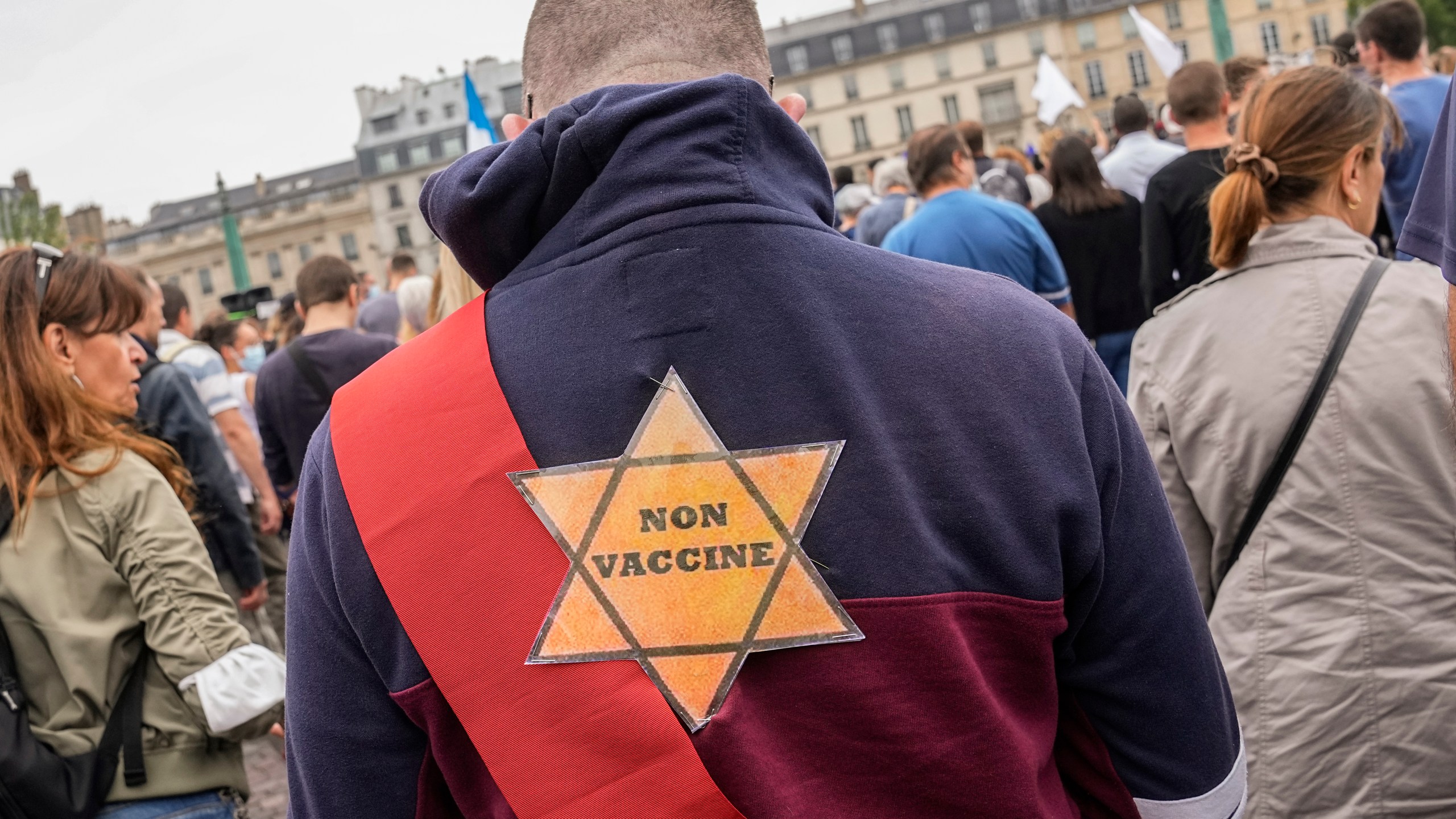 A star that reads, not vaccinated is attached on the back of an Anti-vaccine protesters during a rally in Paris, Saturday, July 17, 2021. A Holocaust survivor, French officials and anti-racism groups are denouncing anti-vaccination protesters who are comparing themselves to Jews persecuted by the Nazis. Some mostly far-right demonstrators at weekend protests against government vaccine rules wore yellow stars, like those Jews were forced to wear under Nazi rule in World War II. Other demonstrators carried signs evoking the Auschwitz death camp or South Africa's apartheid regime, claiming the French government is unfairly persecuting them as it battles the pandemic. (AP Photo/Michel Euler, File)