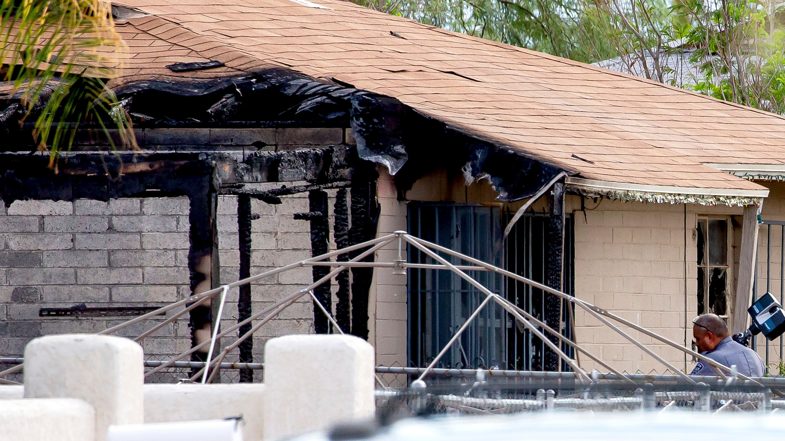 Tucson Police investigators work at the scene of a house fire where a body was found in Tucson, Ariz., Monday, July 19, 2021. A gunman killed one person and wounded several others, including firefighters and paramedics, at the scene of a house fire in Arizona on Sunday before being shot by an officer, authorities said. (Rebecca Sasnett/Arizona Daily Star via AP)