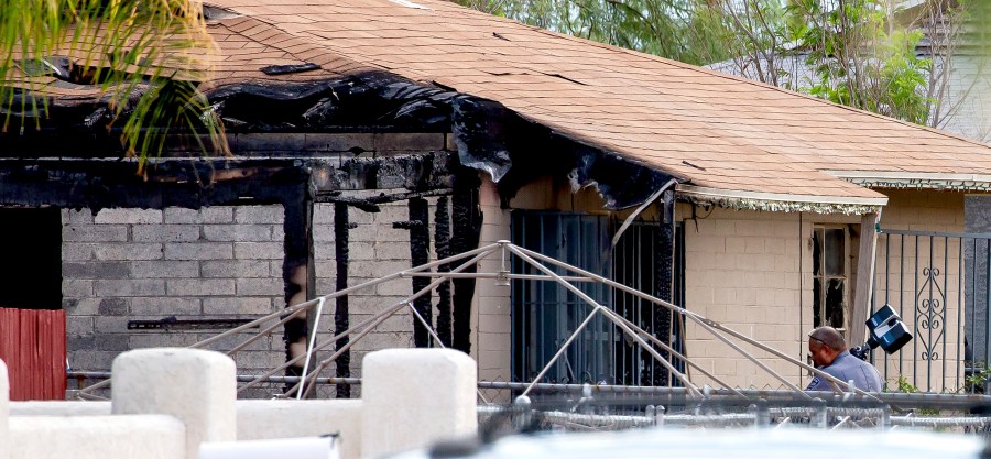 Tucson Police investigators work at the scene of a house fire where a body was found in Tucson, Ariz., Monday, July 19, 2021. A gunman killed one person and wounded several others, including firefighters and paramedics, at the scene of a house fire in Arizona on Sunday before being shot by an officer, authorities said. (Rebecca Sasnett/Arizona Daily Star via AP)