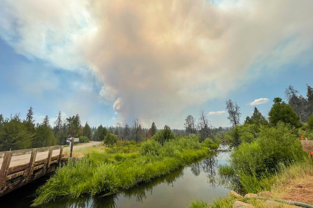 In this photo provided by the Bootleg Fire Incident Command, the Bootleg Fire burns in the background behind the Sycan Marsh in southern Oregon on Saturday, July 17, 2021. (Bootleg Fire Incident Command via AP)