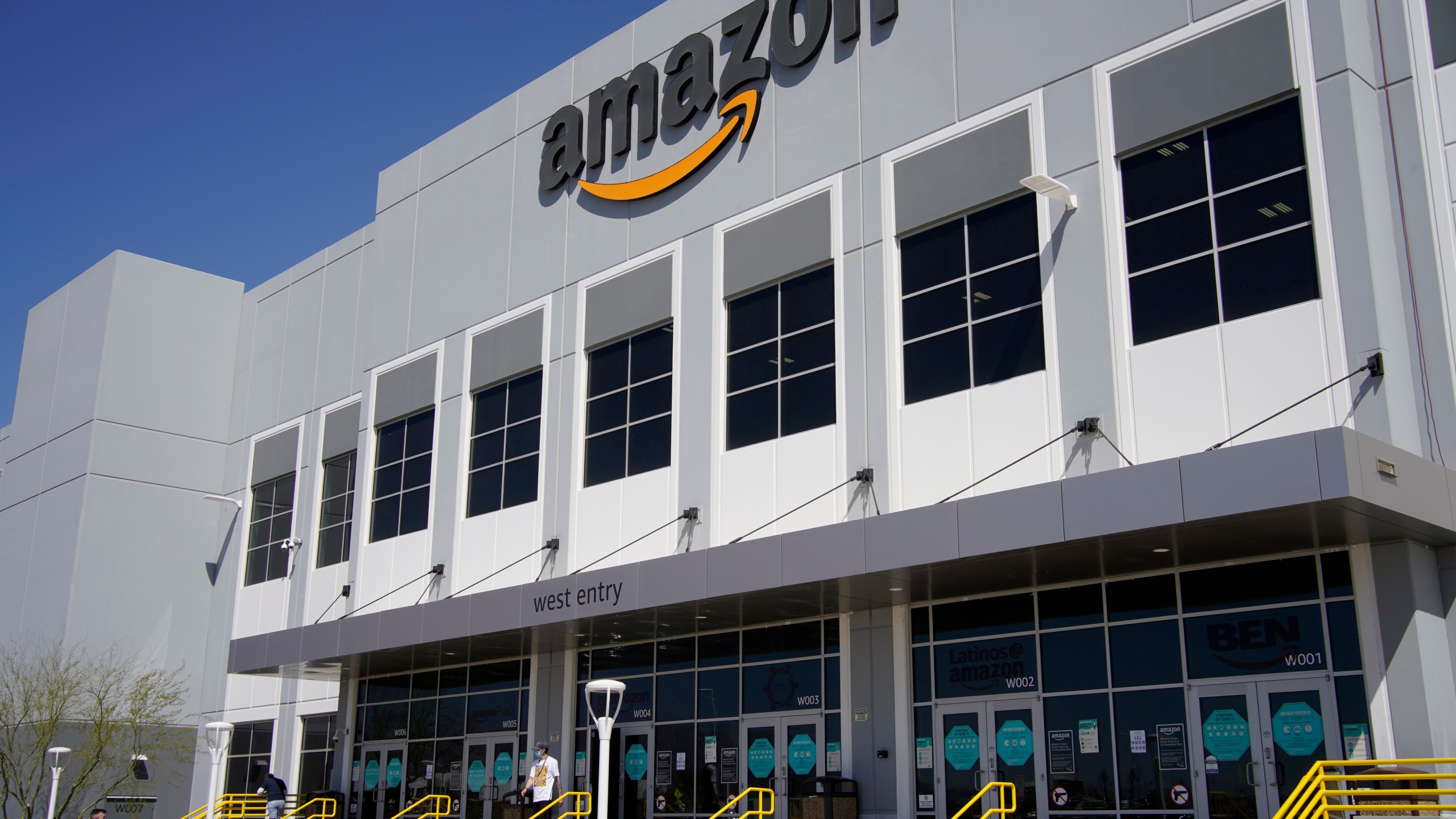 A worker walks out of an Amazon Fulfillment Center, Wednesday, March 31, 2021, in North Las Vegas. Amazon said it will stop testing its workers for COVID-19 at its warehouses at the end of July, citing the availability of vaccines and free testing. (AP Photo/John Locher)