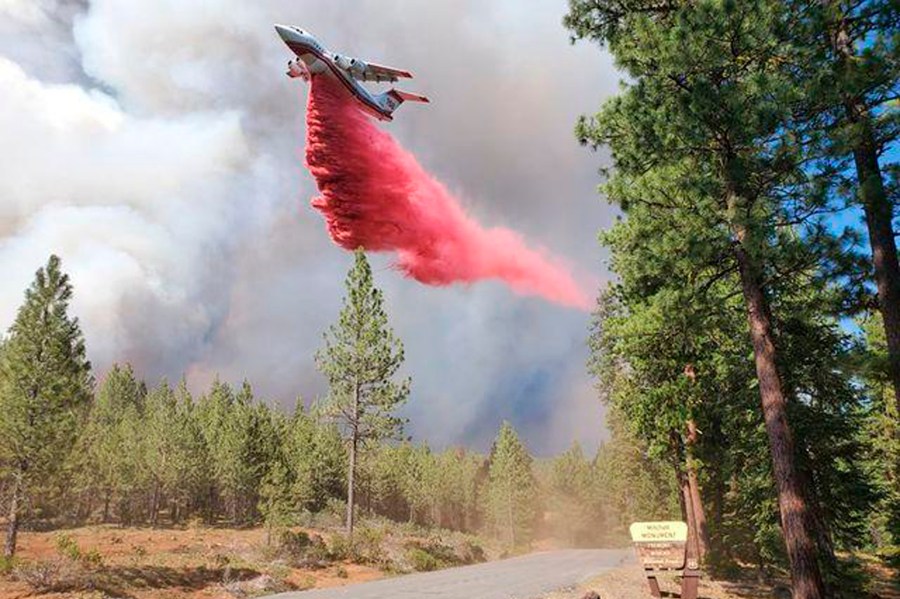 In this photo provided by the Bootleg Fire Incident Command, a tanker drops retardant over the Mitchell Monument area at the Bootleg Fire in southern Oregon on Saturday, July 17, 2021. The 569-square-mile (1,474 square kilometers) Bootleg Fire is burning 300 miles (483 kilometers) southeast of Portland in and around the Fremont-Winema National Forest, a vast expanse of old-growth forest, lakes and wildlife refuges. (Bootleg Fire Incident Command via AP)