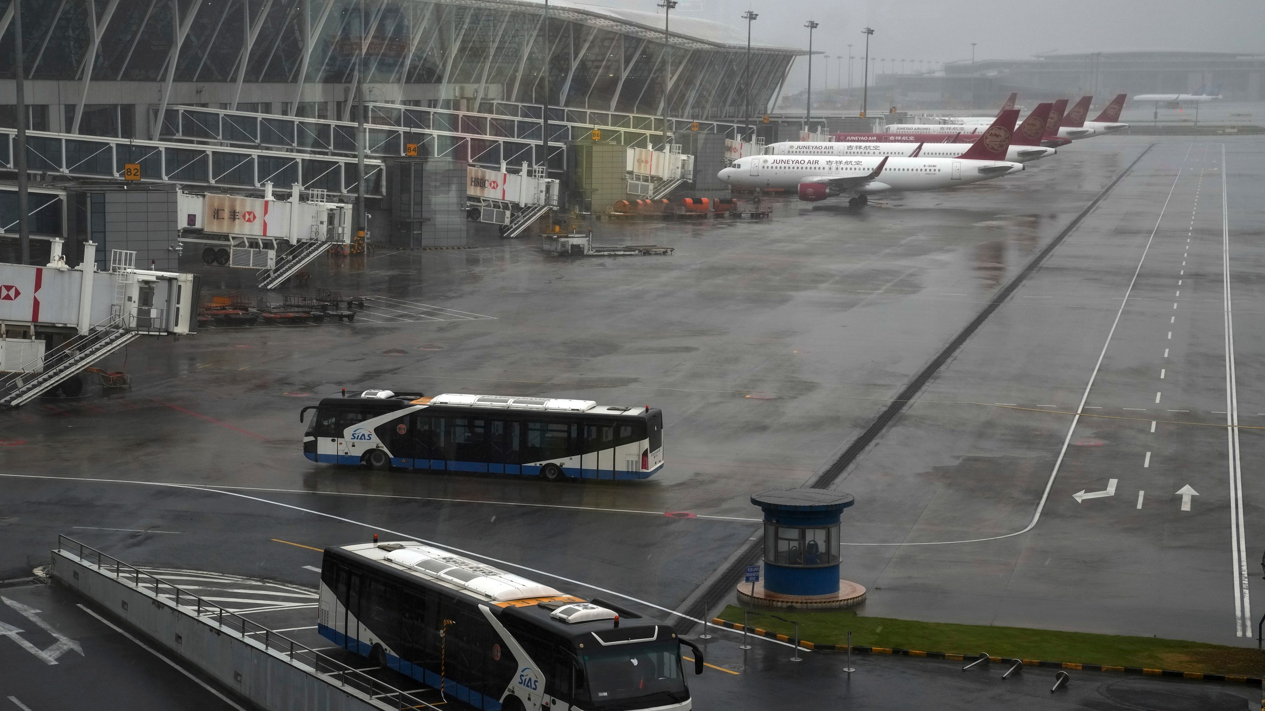 Buses and passenger airplanes are parked on the tarmac after all flights were canceled at Pudong International Airport in Shanghai, China, Sunday, July 25, 2021. (AP Photo/Andy Wong)