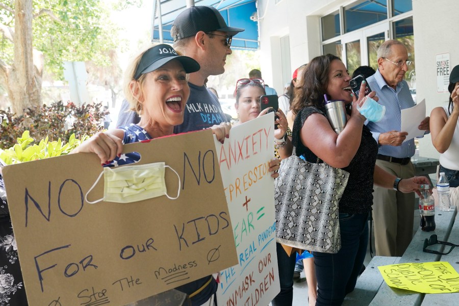 Joann Marcus of Fort Lauderdale, left, cheers as she listens to the Broward School Board's emergency meeting, Wednesday, July 28, 2021, in Fort Lauderdale, Fla. (AP Photo/Marta Lavandier)