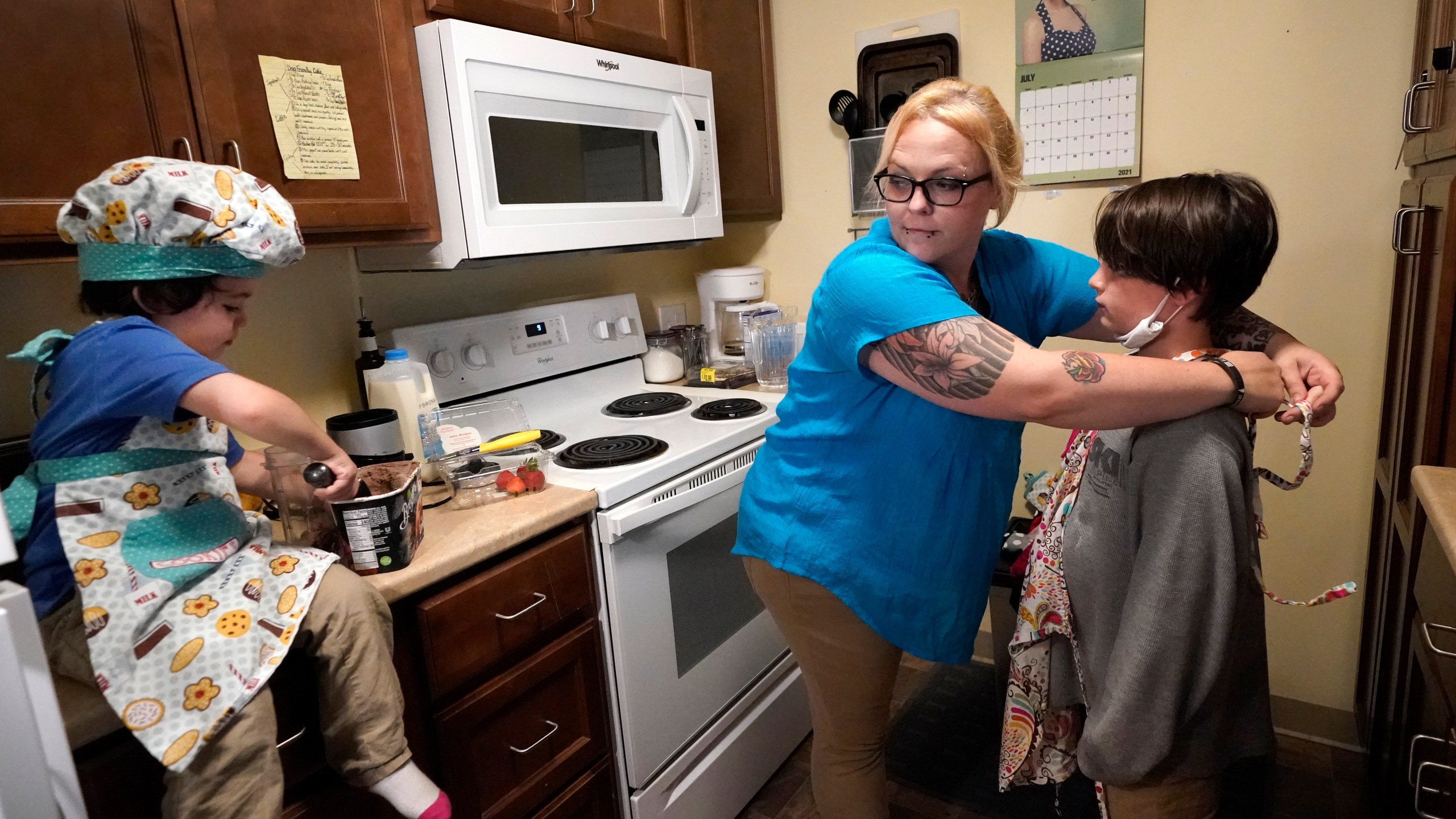 In this July 28, 2021 photo, Christina Darling plays with her sons Kayden, 10, left, and Brennan, 4, at home in Nashua, N.H. Darling and her family have qualified for the expanded child tax credit, part of President Joe Biden's $1.9 trillion coronavirus relief package. "Every step closer we get to a livable wage is beneficial. That is money that gets turned around and spent on the betterment of my kids and myself," said Darling, a housing resource coordinator who had been supplementing her $35,000-a-year salary with monthly visits to the Nashua Soup Kitchen and Shelter's food pantry. (AP Photo/Elise Amendola)