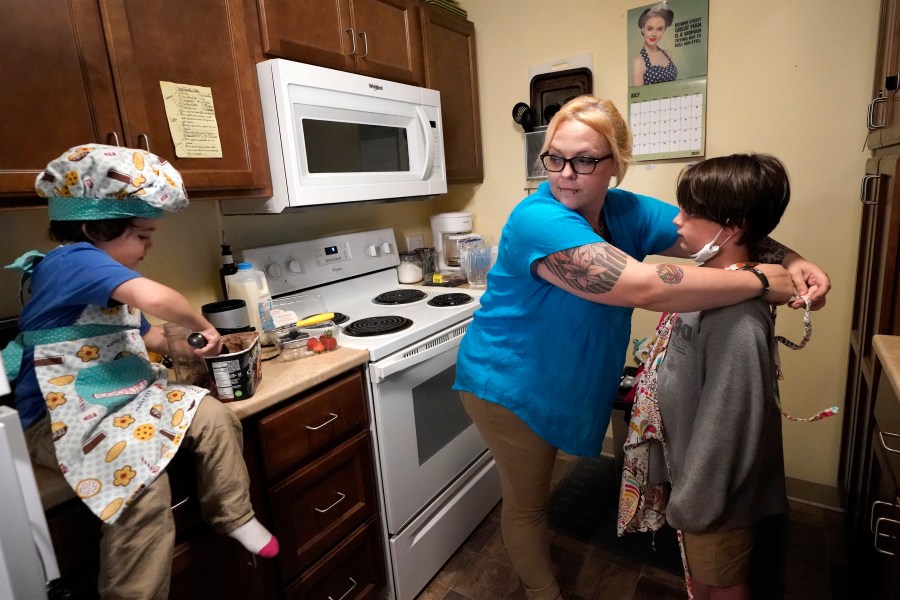 In this July 28, 2021 photo, Christina Darling plays with her sons Kayden, 10, left, and Brennan, 4, at home in Nashua, N.H. Darling and her family have qualified for the expanded child tax credit, part of President Joe Biden's $1.9 trillion coronavirus relief package. "Every step closer we get to a livable wage is beneficial. That is money that gets turned around and spent on the betterment of my kids and myself," said Darling, a housing resource coordinator who had been supplementing her $35,000-a-year salary with monthly visits to the Nashua Soup Kitchen and Shelter's food pantry. (AP Photo/Elise Amendola)