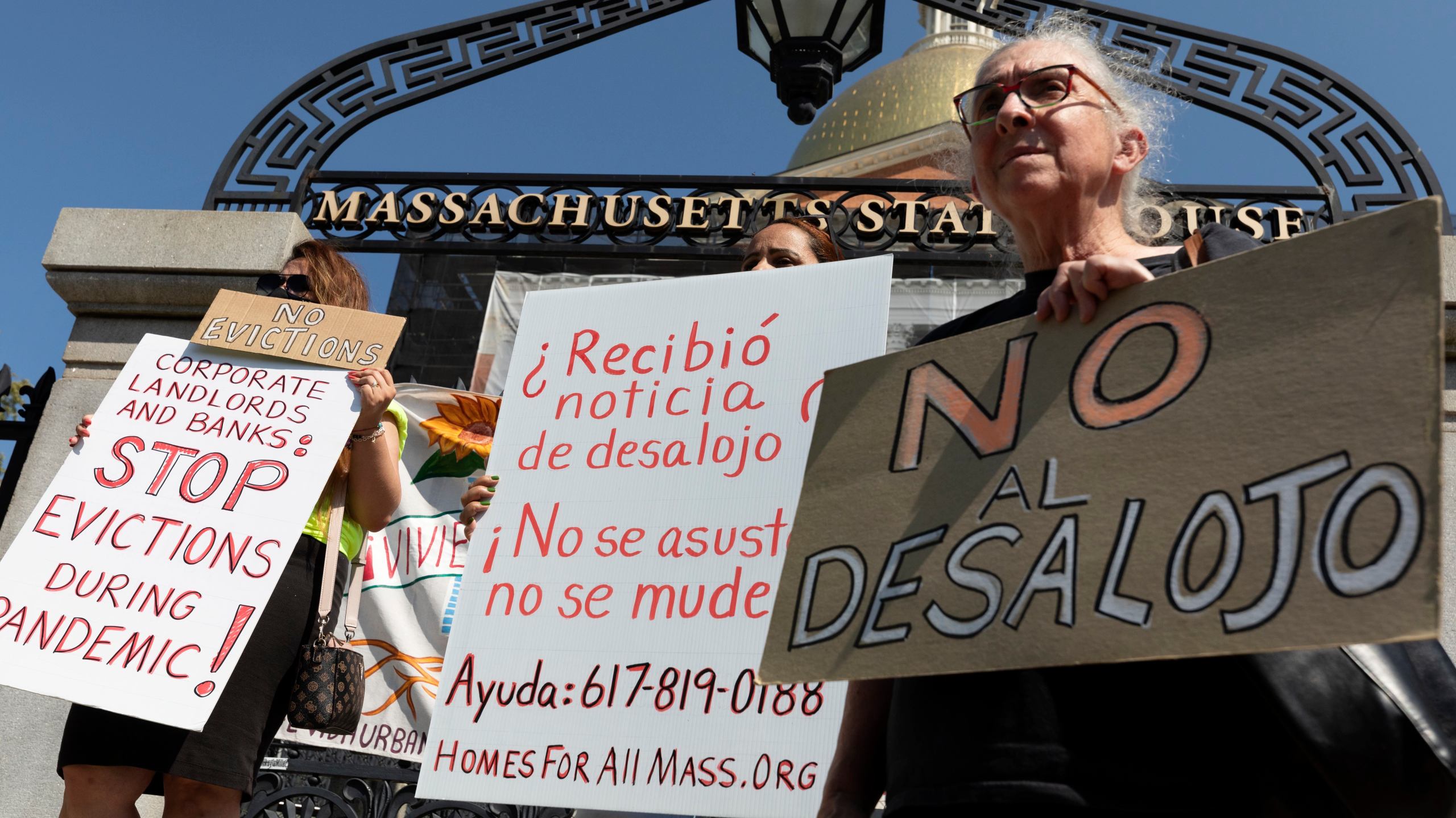 People from a coalition of housing justice groups hold signs protesting evictions during a news conference outside the Statehouse, Friday, July 30, 2021, in Boston. (AP Photo/Michael Dwyer)