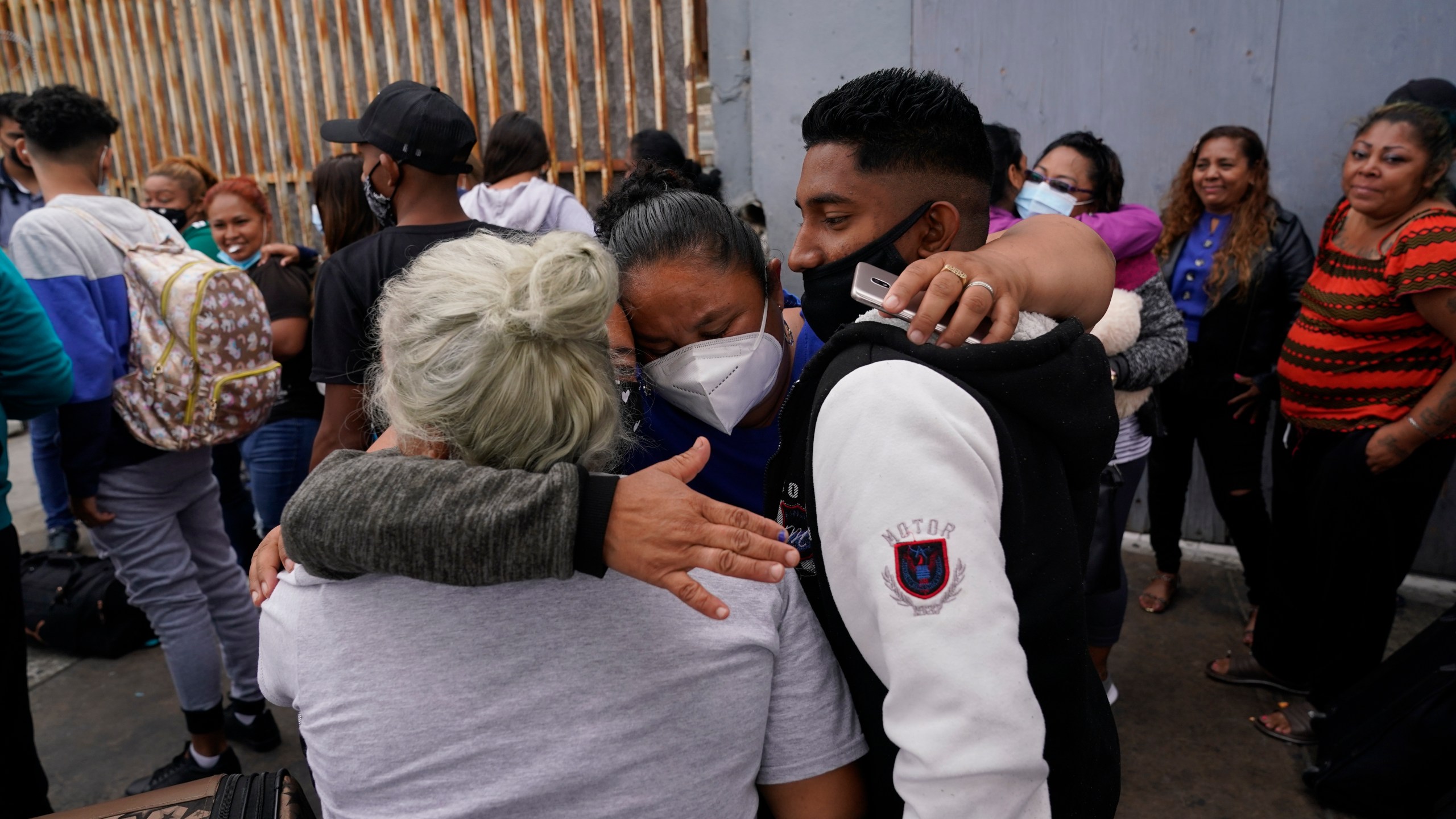 In this July 5, 2021, file photo, Alex Cortillo, right, of Honduras gets a hug from Erika Valladares Ponce, of Honduras, center, and others, as he waits to cross into the United States to begin the asylum process in Tijuana, Mexico. Two nongovernmental organizations said Friday, July 30, 2021, that they are ending cooperation with the Biden Administration to identify the most vulnerable migrants waiting in Mexico to be admitted to the United States to seek asylum. (AP Photo/Gregory Bull, File)