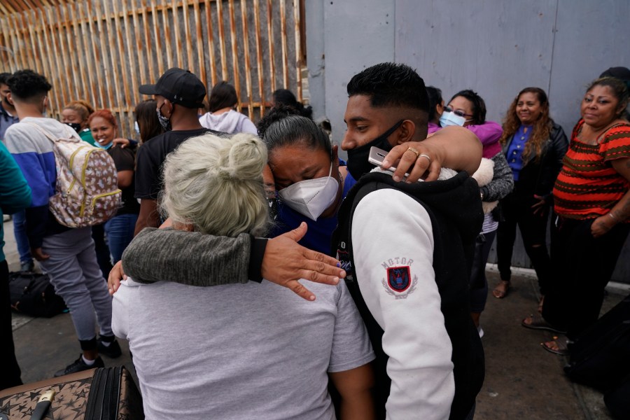 In this July 5, 2021, file photo, Alex Cortillo, right, of Honduras gets a hug from Erika Valladares Ponce, of Honduras, center, and others, as he waits to cross into the United States to begin the asylum process in Tijuana, Mexico. Two nongovernmental organizations said Friday, July 30, 2021, that they are ending cooperation with the Biden Administration to identify the most vulnerable migrants waiting in Mexico to be admitted to the United States to seek asylum. (AP Photo/Gregory Bull, File)