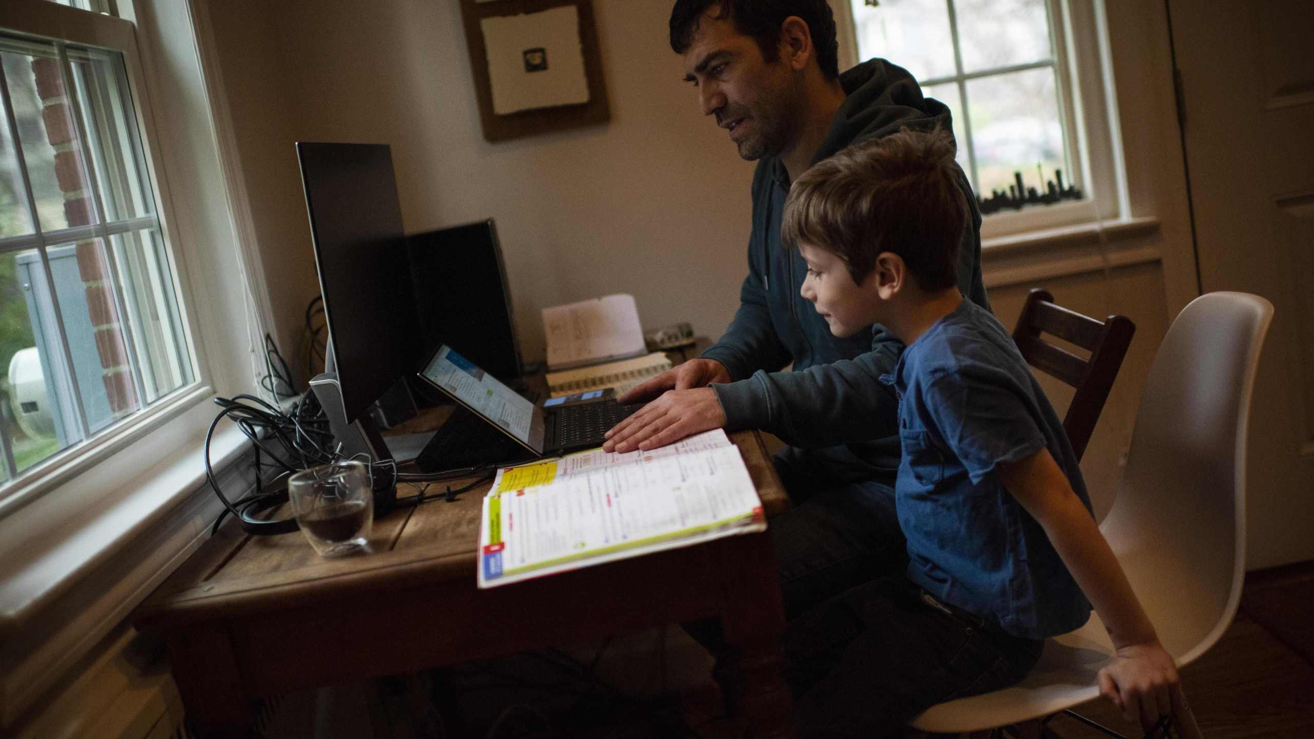 Joachim, 8, whose school was closed following the Coronavirus outbreak, does school exercises at home with his dad Pierre-Yves in Washington on March 20, 2020. (Eric Baradat/AFP via Getty Images)