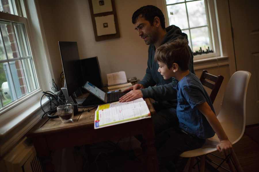 Joachim, 8, whose school was closed following the Coronavirus outbreak, does school exercises at home with his dad Pierre-Yves in Washington on March 20, 2020. (Eric Baradat/AFP via Getty Images)