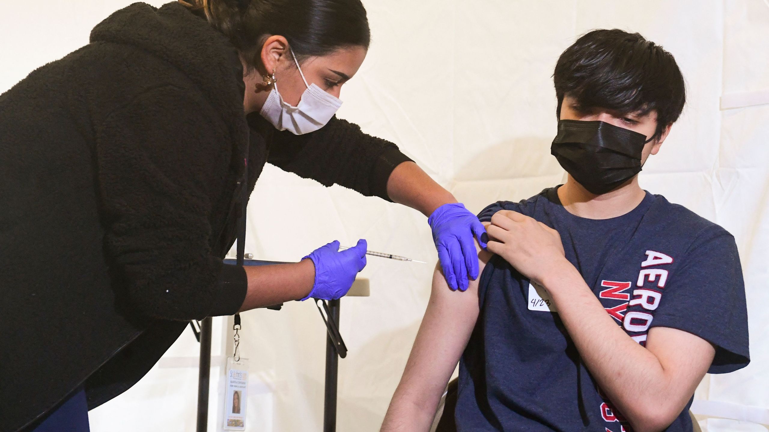 Anthony Briseno, 20, receives his first Pfizer COVID-19 vaccine administered Medical Assistant Karina Cisneros from St. John's Well Child and Family Center at Abraham Lincoln High School in Los Angeles on April 23, 2021. (FREDERIC J. BROWN/AFP via Getty Images)