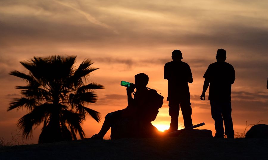 People view the sun set as a child drinks from a water bottle on June 15, 2021 in Los Angeles, as temperatures soar in an early-season heatwave. (Frederic J. BROWN/AFP via Getty Images)