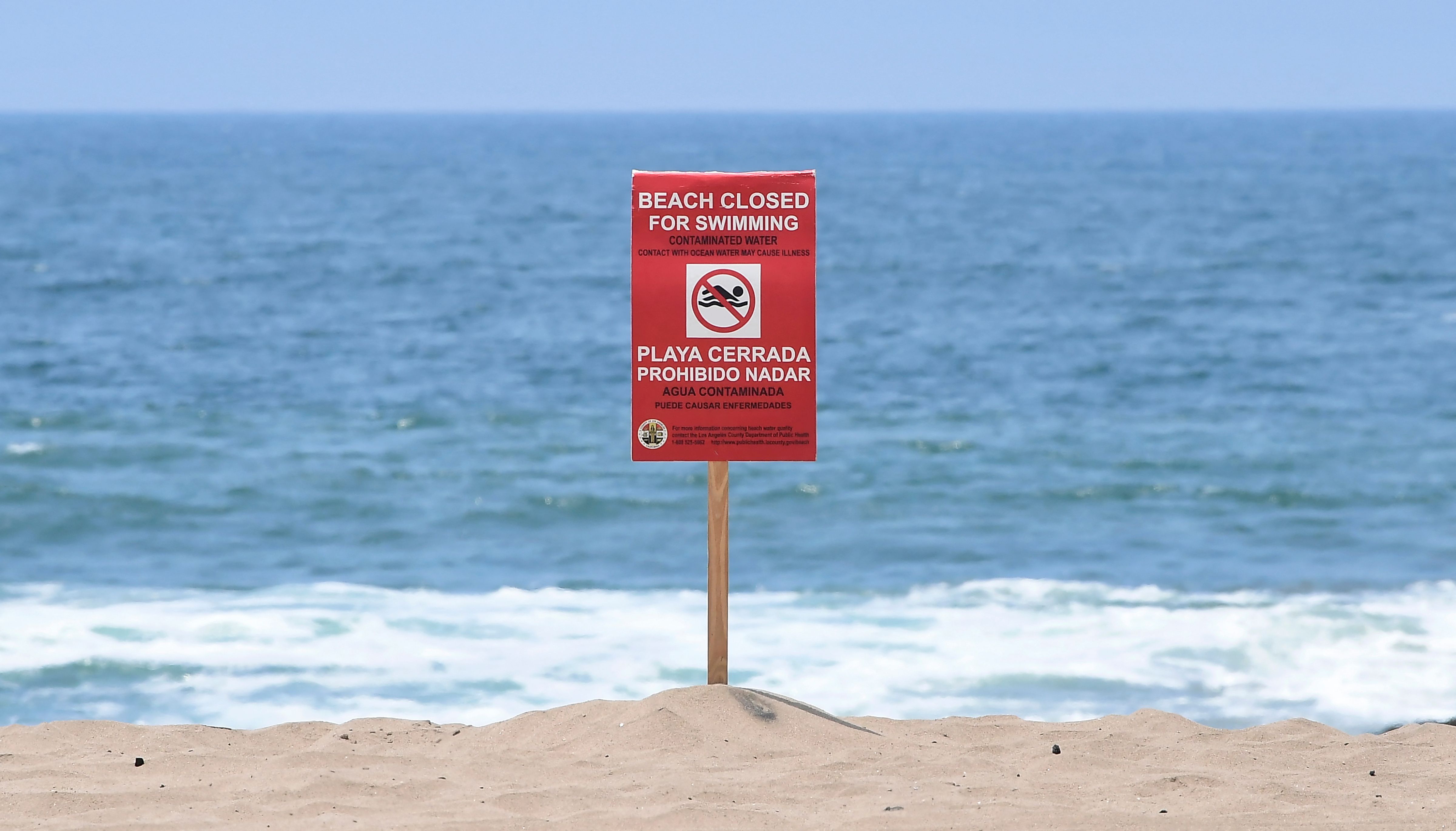 A sign indicates that the Dockweiler State Beach is closed to swimming after a sewage spill in Playa del Rey, in Los Angeles County, California, on July 13, 2021. (FREDERIC J. BROWN/AFP via Getty Images)