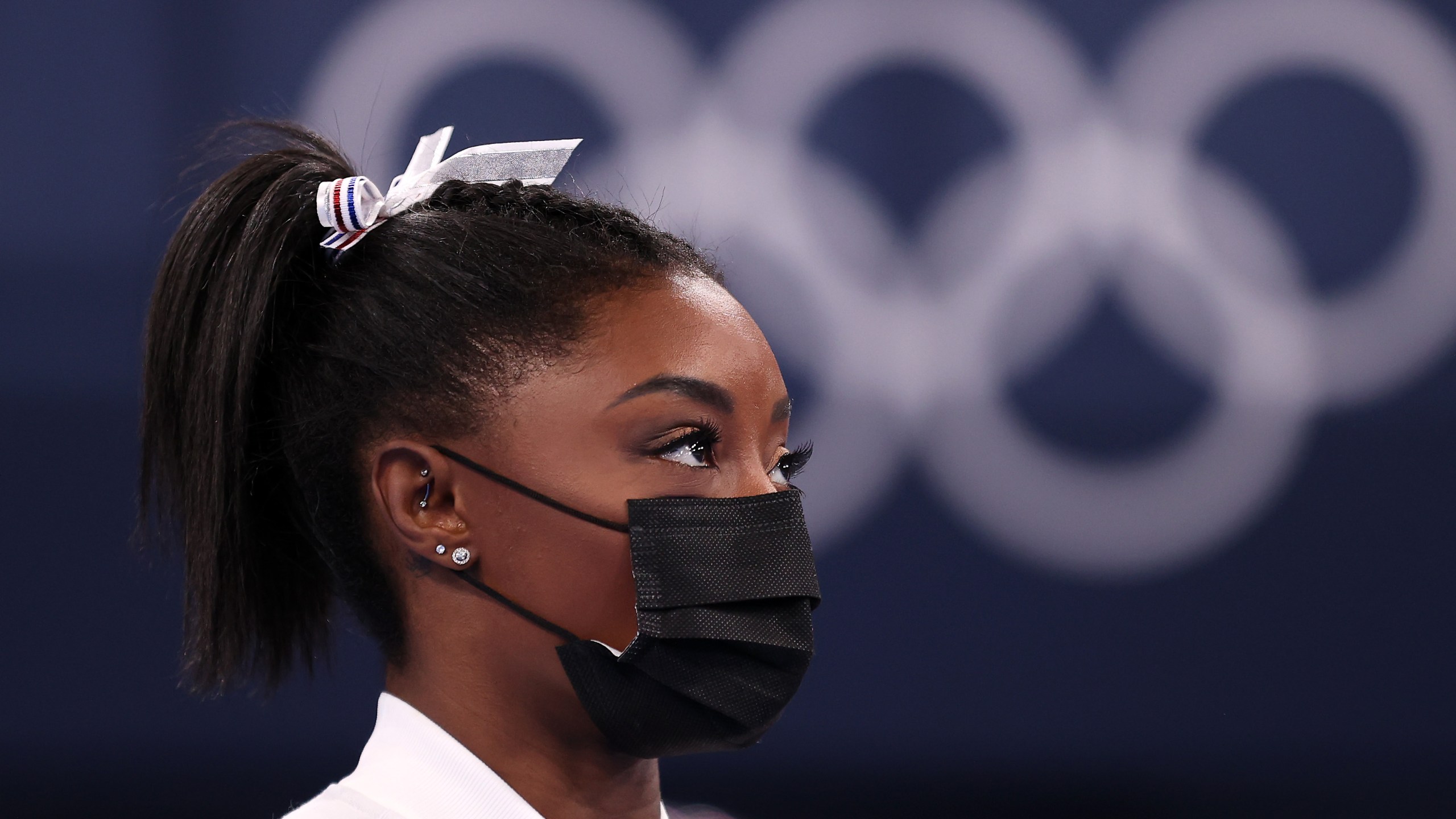 Simone Biles of Team United States watches her team perform on bars after pulling out of the competition after only competing on the vault during the Women's Team Final on day four on day four of the Tokyo 2020 Olympic Games at Ariake Gymnastics Centre on July 27, 2021, in Tokyo, Japan.(Laurence Griffiths/Getty Images)