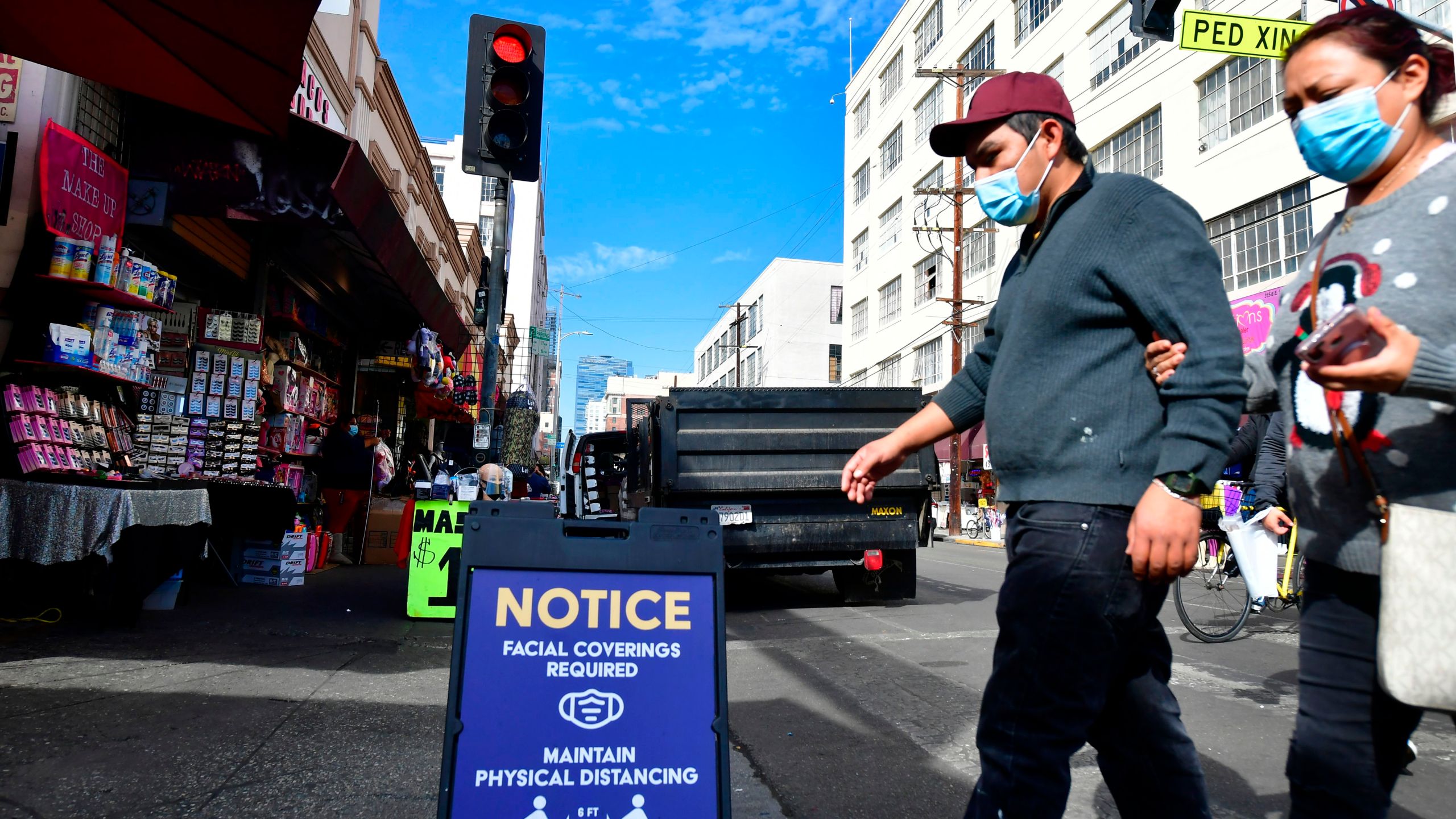 A signboard reminds people of the face covering requirement as pedestrians wear facemasks due to the coronavirus in Los Angeles on Nov. 12, 2020. (Frederic J. Brown/AFP via Getty Images)