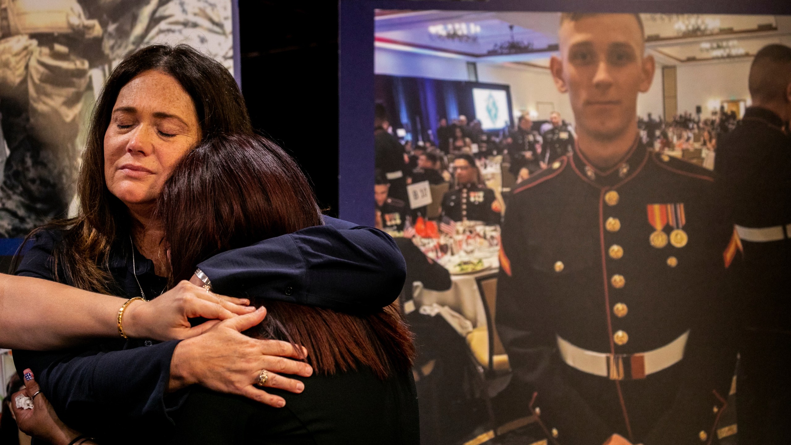 Christiana Sweetwood, mother of Marine Lance Corporal Chase Sweetwood, hand coming from left, Aleta Bath, mother of Private First Class Evan Bath and Lupita Garcia, mother of Marine Lance Corporal Marco Barranco embrace each other at a press conference next to a picture of Chase Sweetwood July 29, 2021, in Oceanside, Calif. (Sam Hodgson/The San Diego Union-Tribune via AP)