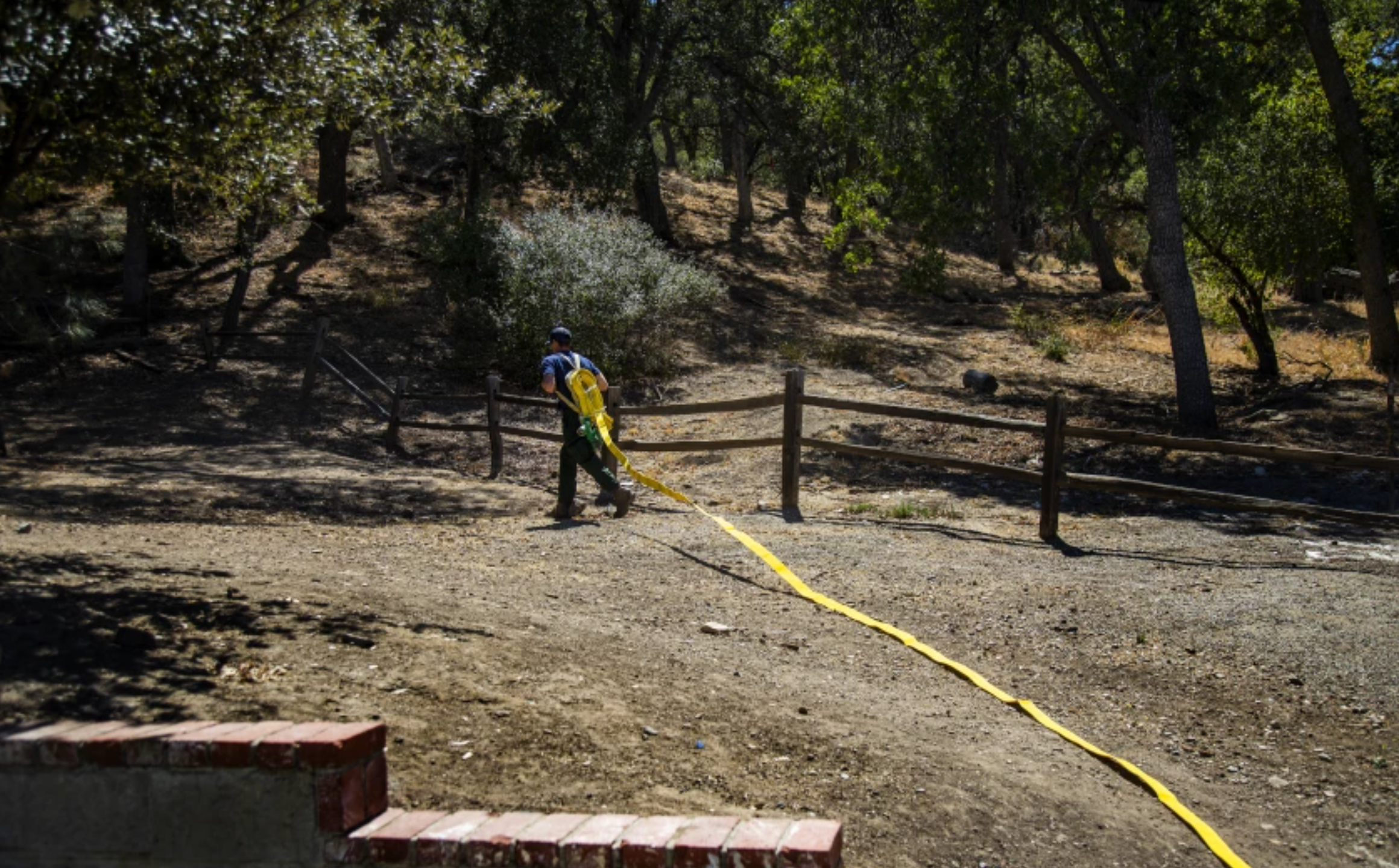 U.S. Forest Service firefighter Nick Browne deploys a fire hose pack during training in Castaic. Crews in the bone-dry forest must aim for 100% mop-up, meaning they must extinguish every ember. “There are no shortcuts here,” he said.(Gina Ferazzi / Los Angeles Times)