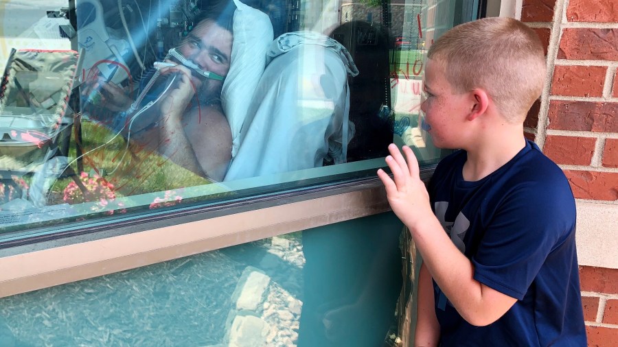 Six-year-old Brody Barker waves to his father, Daryl, from outside his hospital room on Monday, July 26, 2021, in Osage Beach, Mo. Brody and his mother, Billie, have spent nearly three weeks camped outside Lake Regional Hospital's Intensive Care Unit as Barker recovers from COVID-19. "I think that him being able to see us made him fight more," she said. (AP Photo/Sarah Blake Morgan)