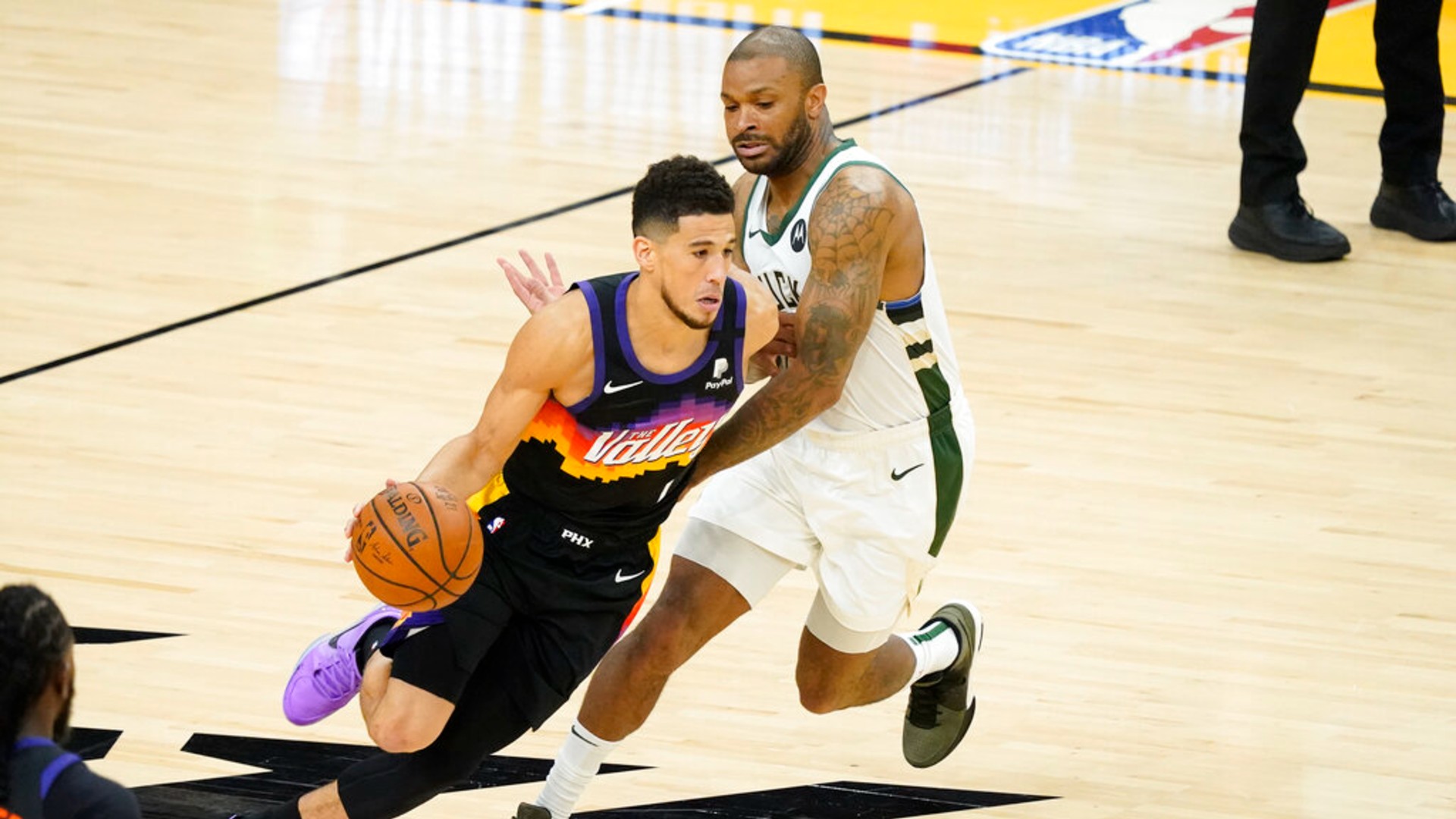 Phoenix Suns guard Devin Booker, left, dribbles against Milwaukee Bucks forward P.J. Tucker during the first half of Game 2 of basketball's NBA Finals, Thursday, July 8, 2021, in Phoenix. (AP Photo/Matt York)