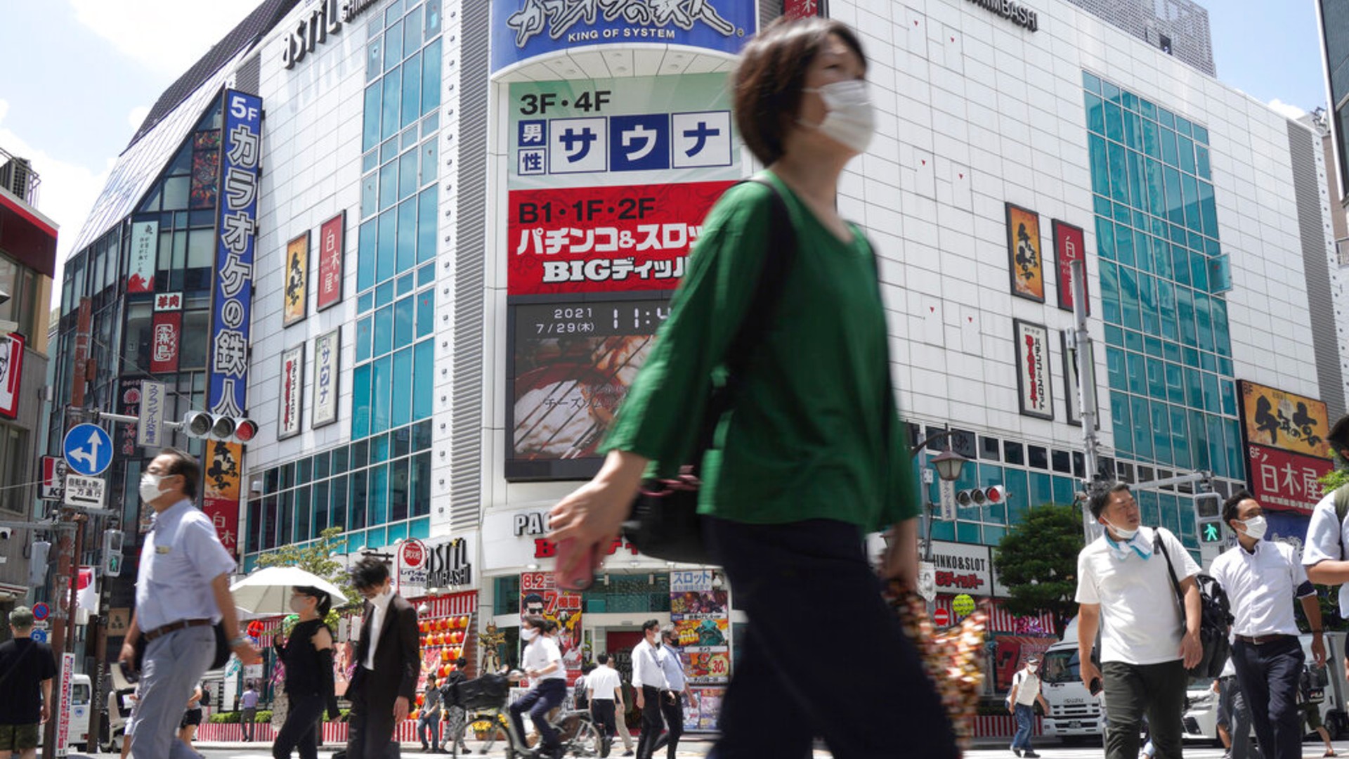 People walk across a crossing near Shimbashi Station in Tokyo Thursday, July 29, 2021, a day after the record-high coronavirus cases were found in the Olympics host city. (AP Photo/Kantaro Komiya)