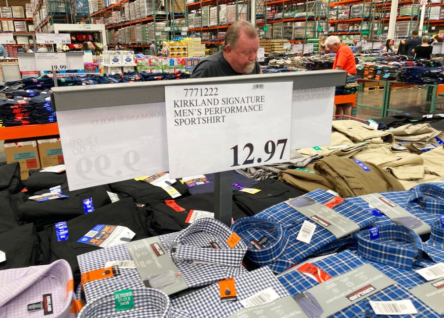 A sign displays the price for shirts as a shopper peruses the offerings at a Costco warehouse in this photograph taken Thursday, June 17, 2021, in Lone Tree, Colo. (AP Photo/David Zalubowski)