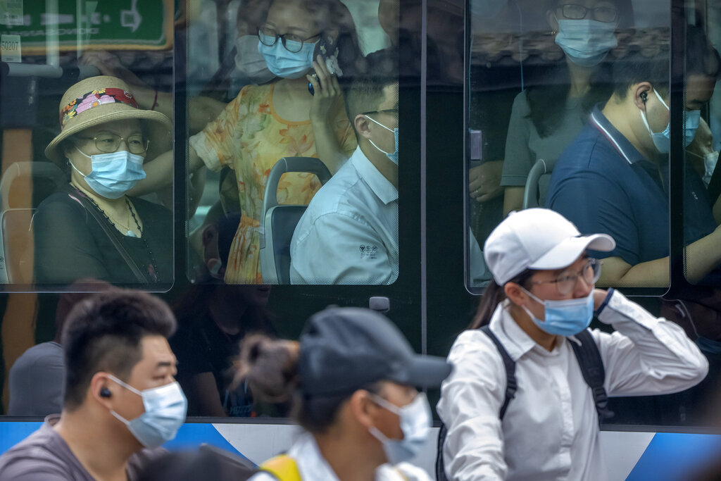 People wearing face masks to protect against COVID-19 ride on a bus during the morning rush hour in Beijing, Wednesday, Aug. 4, 2021. (AP Photo/Mark Schiefelbein)