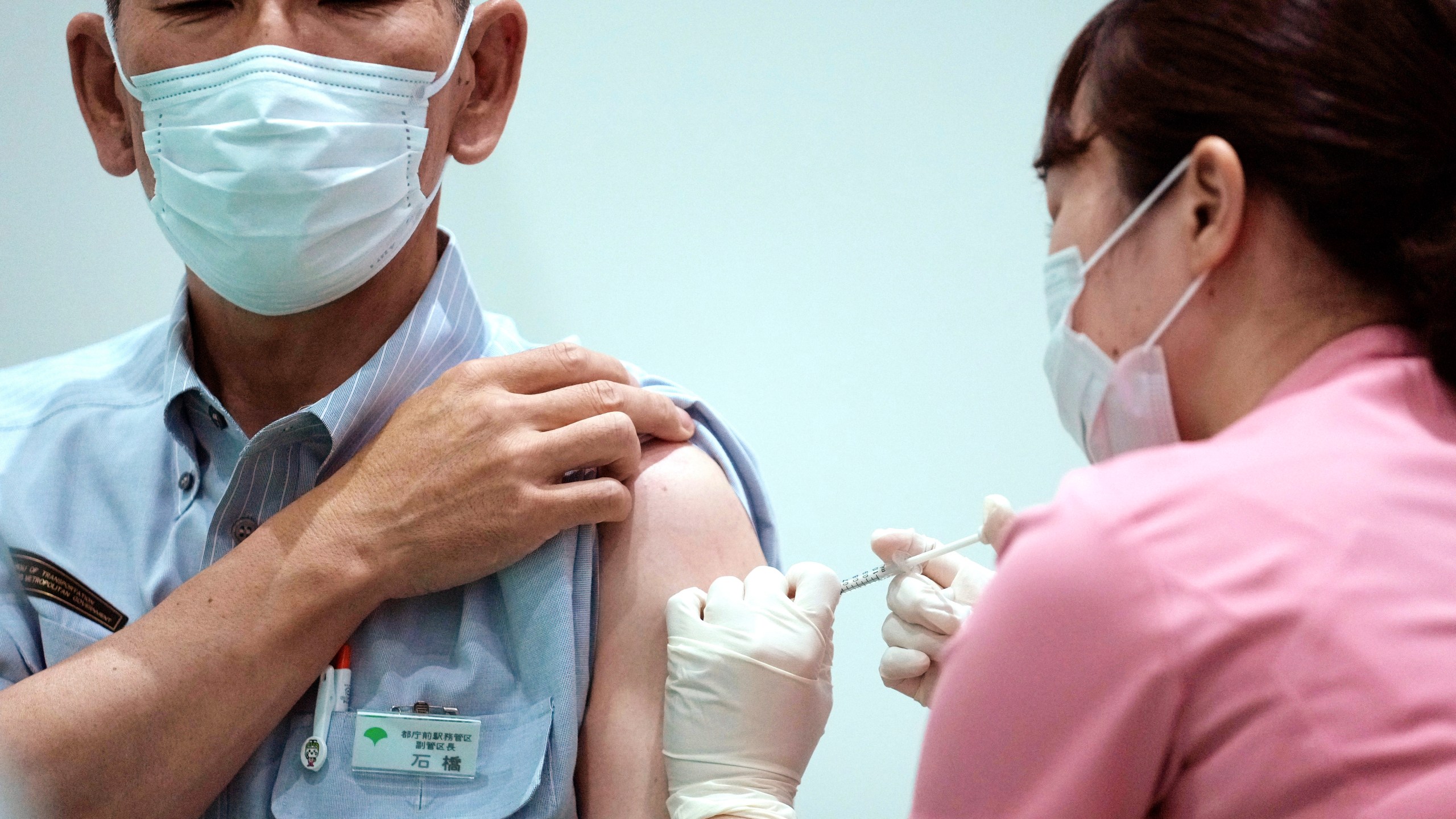 In this July 1, 2021, file photo, a Tokyo Metropolitan government employee takes the Moderna's COVID-19 vaccine shot at a vaccination center in the government building in Tokyo. The Tokyo Olympics are over, but it's still vacation season in Japan, and many are ignoring government pleas to avoid travel and stay away from bars and restaurants even as the coronavirus spikes at record levels. (AP Photo/Eugene Hoshiko, File)