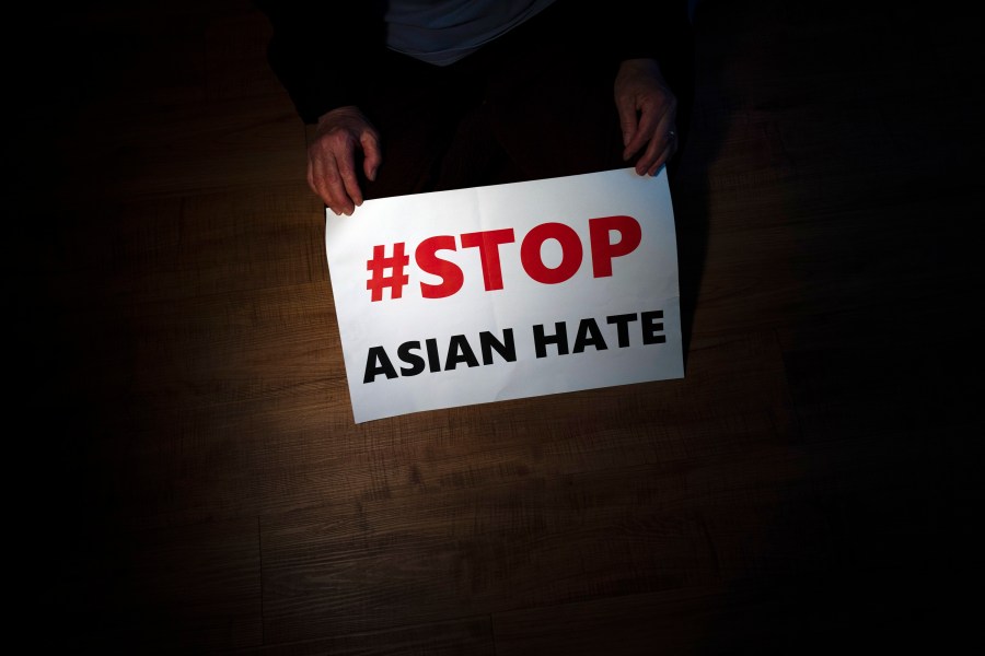 In this March 31, 2021, file photo, Jen Ho Lee, a 76-year-old South Korean immigrant, poses in her apartment in Los Angeles with a sign from a recent rally against anti-Asian hate crimes she attended.(AP Photo/Jae C. Hong, File)