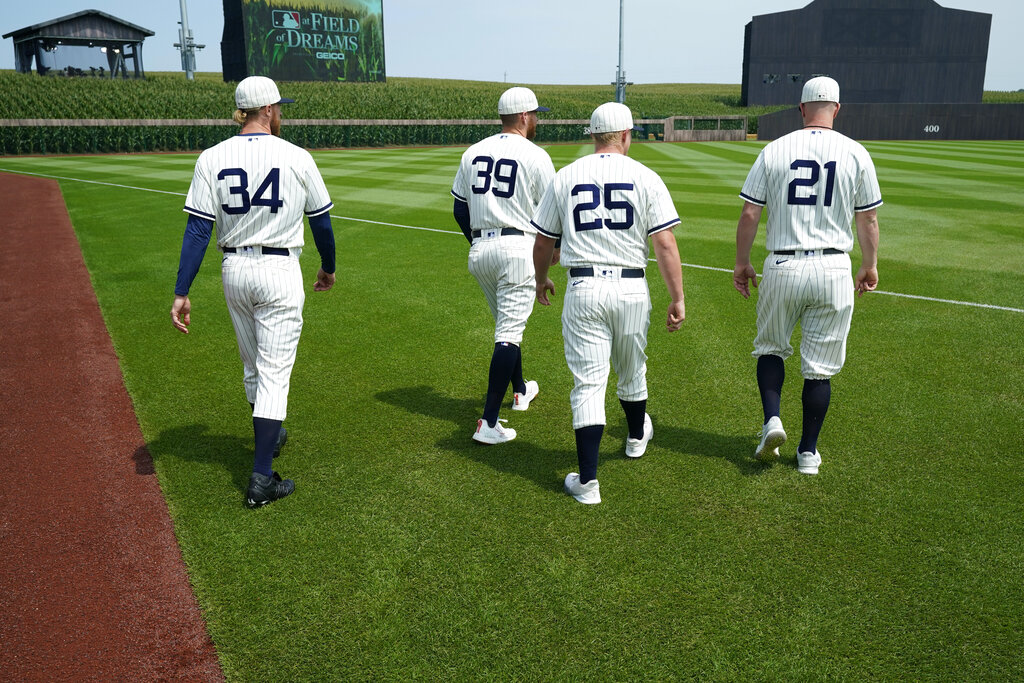 Chicago White Sox players Michael Kopech (34), Aaron Bummer (39), Andrew Vaughn (25) and Zack Collins (21) walk on the field before a baseball game against the New York Yankees, Thursday, Aug. 12, 2021, in Dyersville, Iowa. (AP Photo/Charlie Neibergall)