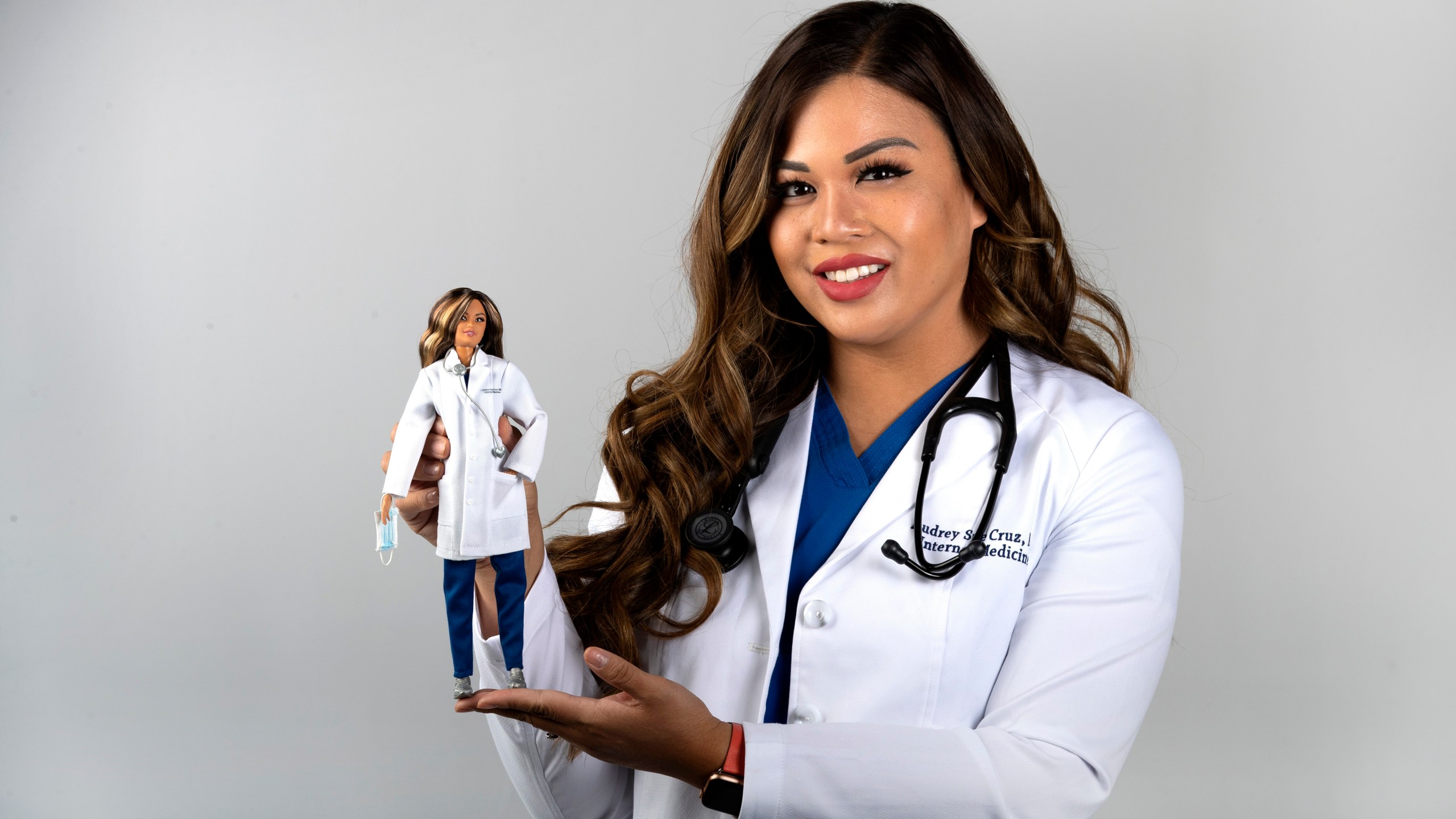 Dr. Audrey Sue Cruz, a doctor of internal medicine, poses with a Barbie doll, created in her likeness, in the Las Vegas Sun studio in Henderson, Nev., Saturday, Aug. 7, 2021. The doll based on Dr. Cruz is one of six limited-edition Barbie dolls to honor frontline healthcare workers. (Steve Marcus/Las Vegas Sun via AP)