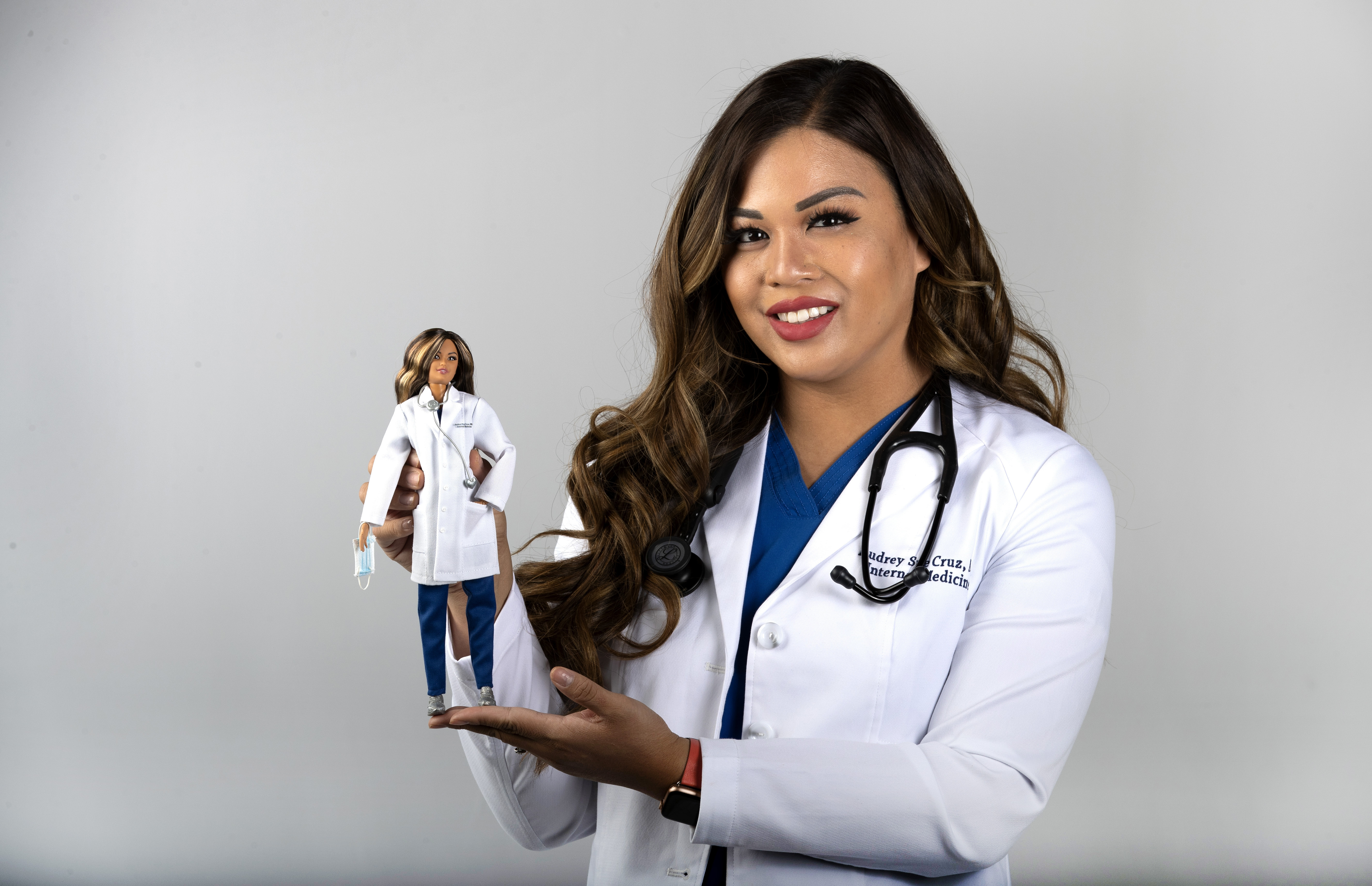 Dr. Audrey Sue Cruz, a doctor of internal medicine, poses with a Barbie doll, created in her likeness, in the Las Vegas Sun studio in Henderson, Nev., Saturday, Aug. 7, 2021. The doll based on Dr. Cruz is one of six limited-edition Barbie dolls to honor frontline healthcare workers. (Steve Marcus/Las Vegas Sun via AP)