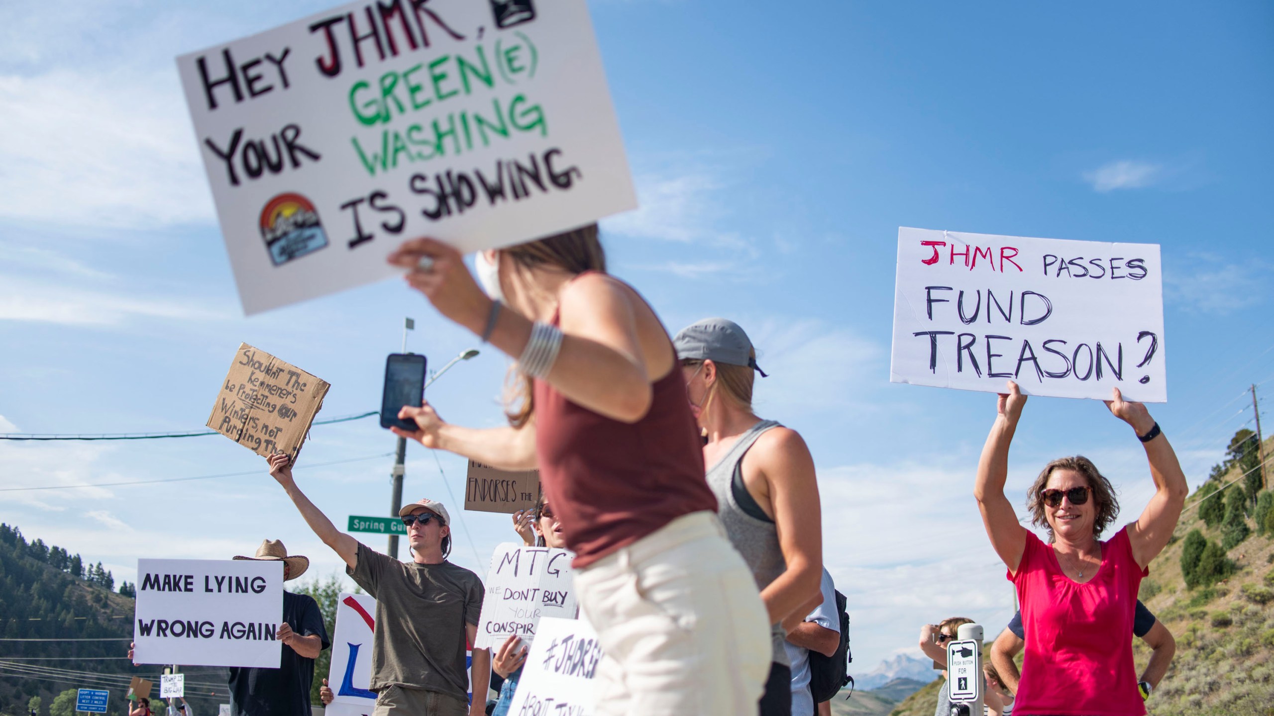 In this Aug. 5, 2021, photo Nikki Kaufman takes a photo of a fellow demonstrator while protesting Jackson Hole Mountain Resort owner Jay Kemmerer's decision to co-host a fundraiser for the House Freedom Fund near Jackson, Wyo. Kaufman and others have called on others to think critically about their ski pass purchases. The outdoor gear and clothing company Patagonia has stopped providing its merchandise for sale at a Wyoming ski resort to protest the owners' sponsorship of a Republican fundraiser featuring Marjorie Taylor Greene and other core supporters of former President Donald Trump. (Meg Potter/Jackson Hole News & Guide via AP)