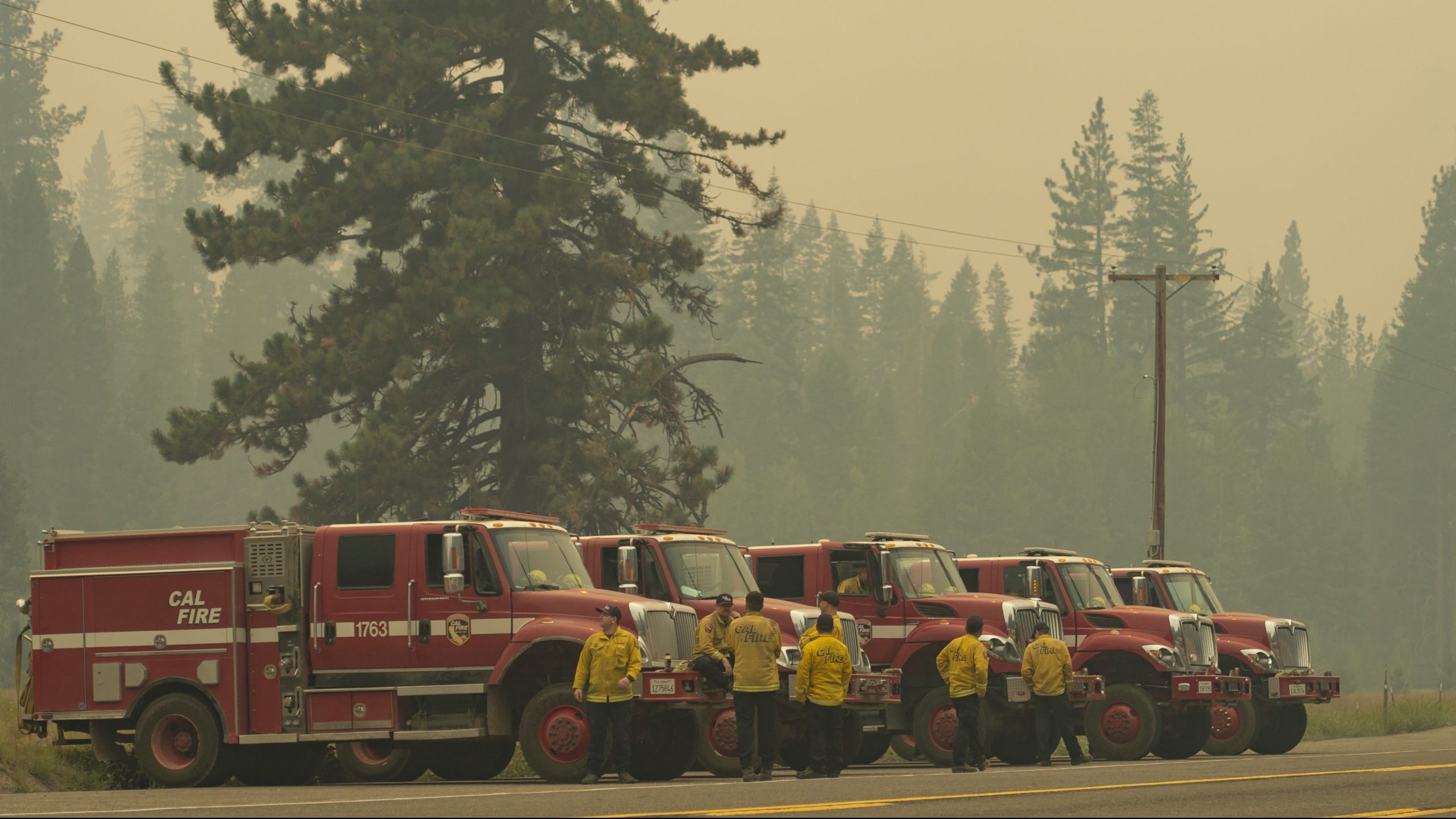 Cal Fire vehicles line up along Highway 50 in Strawberry, Calif., on Aug. 22, 2021, as smoke from the Caldor Fire burning on both side of the route fills the air. (Sara Nevis/The Sacramento Bee via AP)