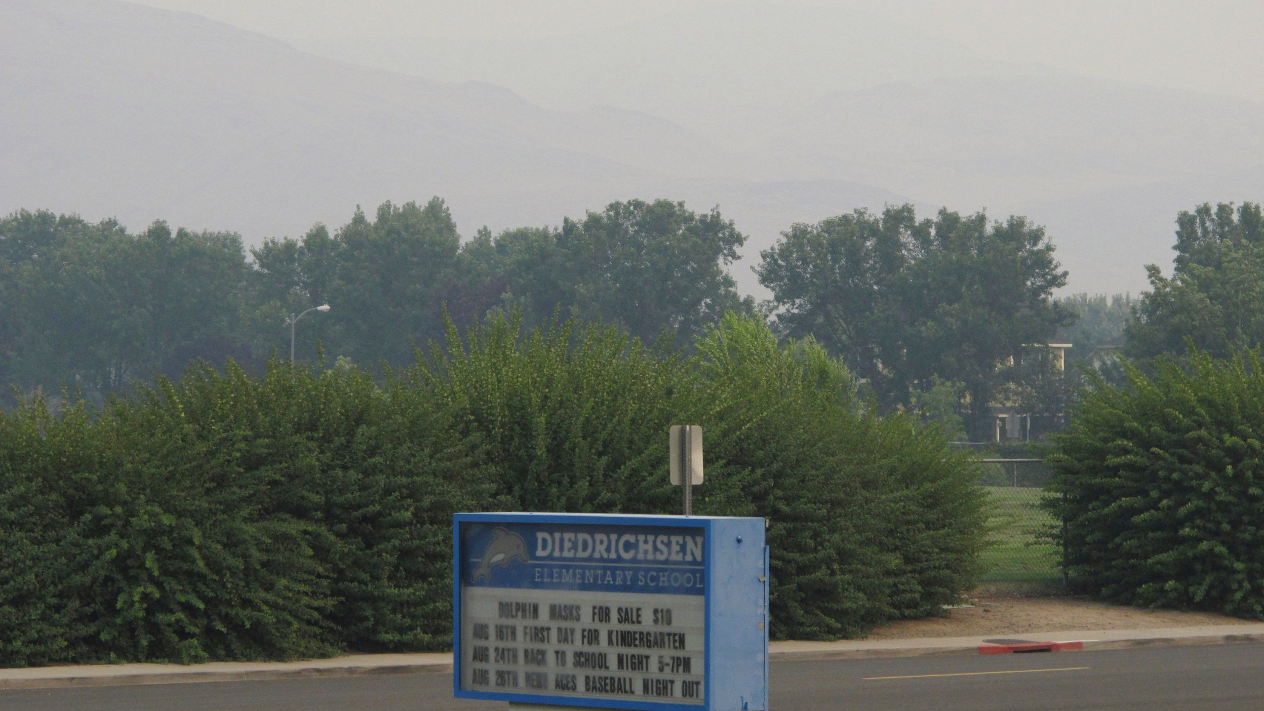 Smoke from wildfires in California obscures the Pah Hah Range, Monday, Aug. 23, 2021, about 1 mile east of Diedrichsen Elementary School in Sparks, Nev., which was closed due to hazardous air quality. The Washoe County School District closed all schools including in Reno, Sparks and parts of Lake Tahoe on Monday due to the health hazard. The county health district also urged the general public to "stay inside as much as possible" due to conditions expected to continue through Wednesday. (AP Photo/Scott Sonner)