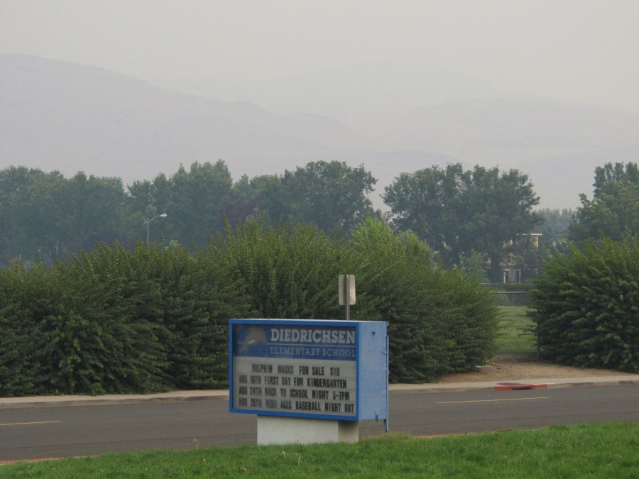 Smoke from wildfires in California obscures the Pah Hah Range, Monday, Aug. 23, 2021, about 1 mile east of Diedrichsen Elementary School in Sparks, Nev., which was closed due to hazardous air quality. The Washoe County School District closed all schools including in Reno, Sparks and parts of Lake Tahoe on Monday due to the health hazard. The county health district also urged the general public to "stay inside as much as possible" due to conditions expected to continue through Wednesday. (AP Photo/Scott Sonner)