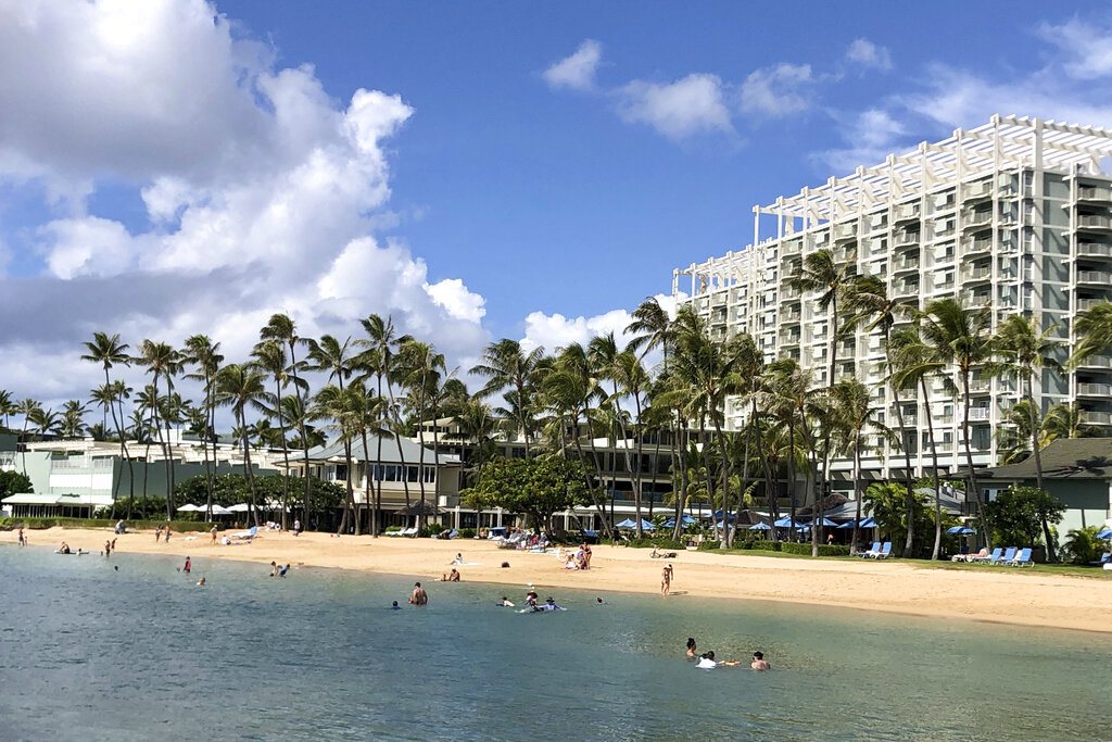 In this Sunday, Nov. 15, 2020, file photo, people are seen on the beach and in the water in front of the Kahala Hotel & Resort in Honolulu. (AP Photo/Jennifer Sinco Kelleher, File)