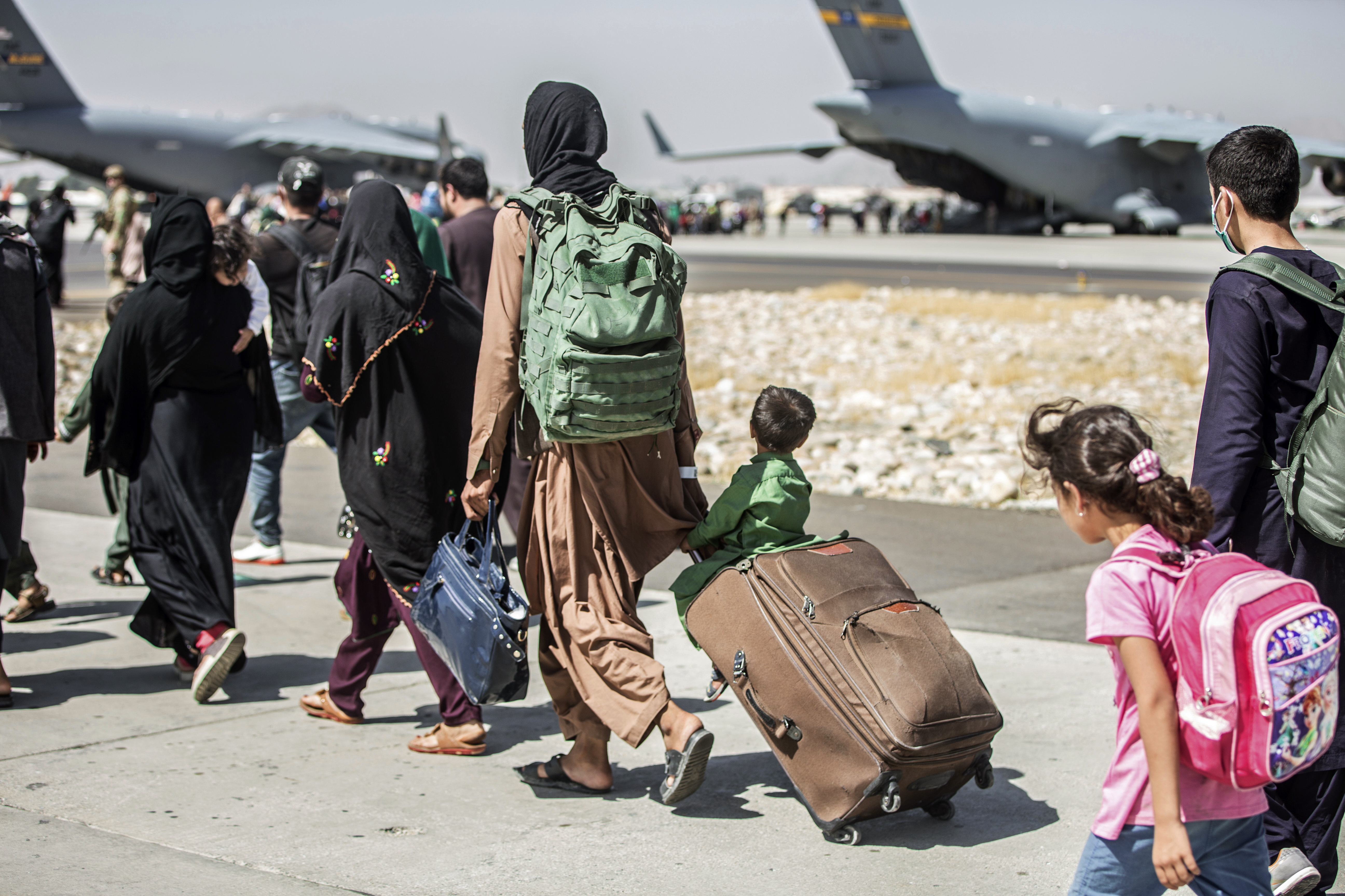 This file photo provided by the U.S. Marine Corps shows families walk towards their flight during ongoing evacuations at Hamid Karzai International Airport, in Kabul, Afghanistan on Aug. 24, 2021. (Sgt. Samuel Ruiz / U.S. Marine Corps via Associated Press)