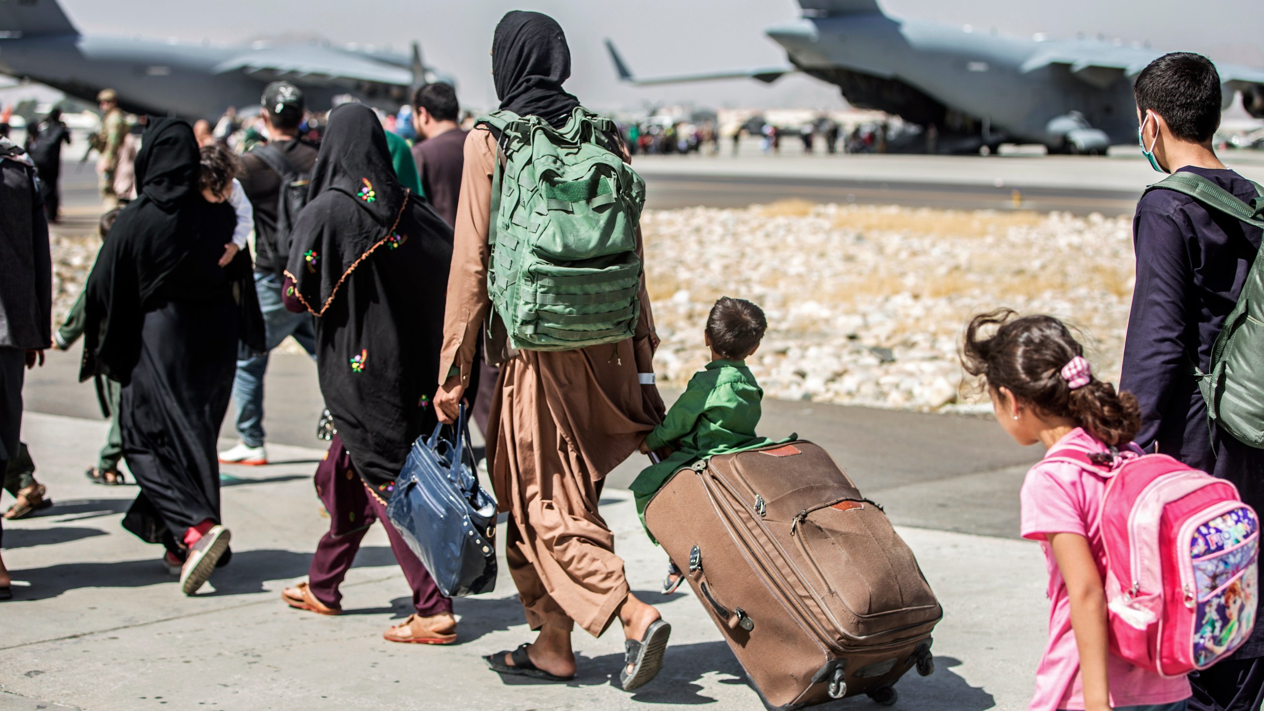 In this Aug. 24, 2021, file photo, provided by the U.S. Marine Corps, families walk towards their flight during ongoing evacuations at Hamid Karzai International Airport, in Kabul, Afghanistan. A school district in a San Diego suburb that is home to a large refugee population says many of its families who had taken summer trips to Afghanistan to see their relatives have gotten stuck there with the chaos following the withdrawal of U.S. troops. (Sgt. Samuel Ruiz/U.S. Marine Corps via AP, File)