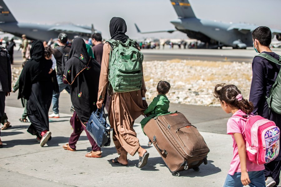 In this Aug. 24, 2021, file photo, provided by the U.S. Marine Corps, families walk towards their flight during ongoing evacuations at Hamid Karzai International Airport, in Kabul, Afghanistan. A school district in a San Diego suburb that is home to a large refugee population says many of its families who had taken summer trips to Afghanistan to see their relatives have gotten stuck there with the chaos following the withdrawal of U.S. troops. (Sgt. Samuel Ruiz/U.S. Marine Corps via AP, File)