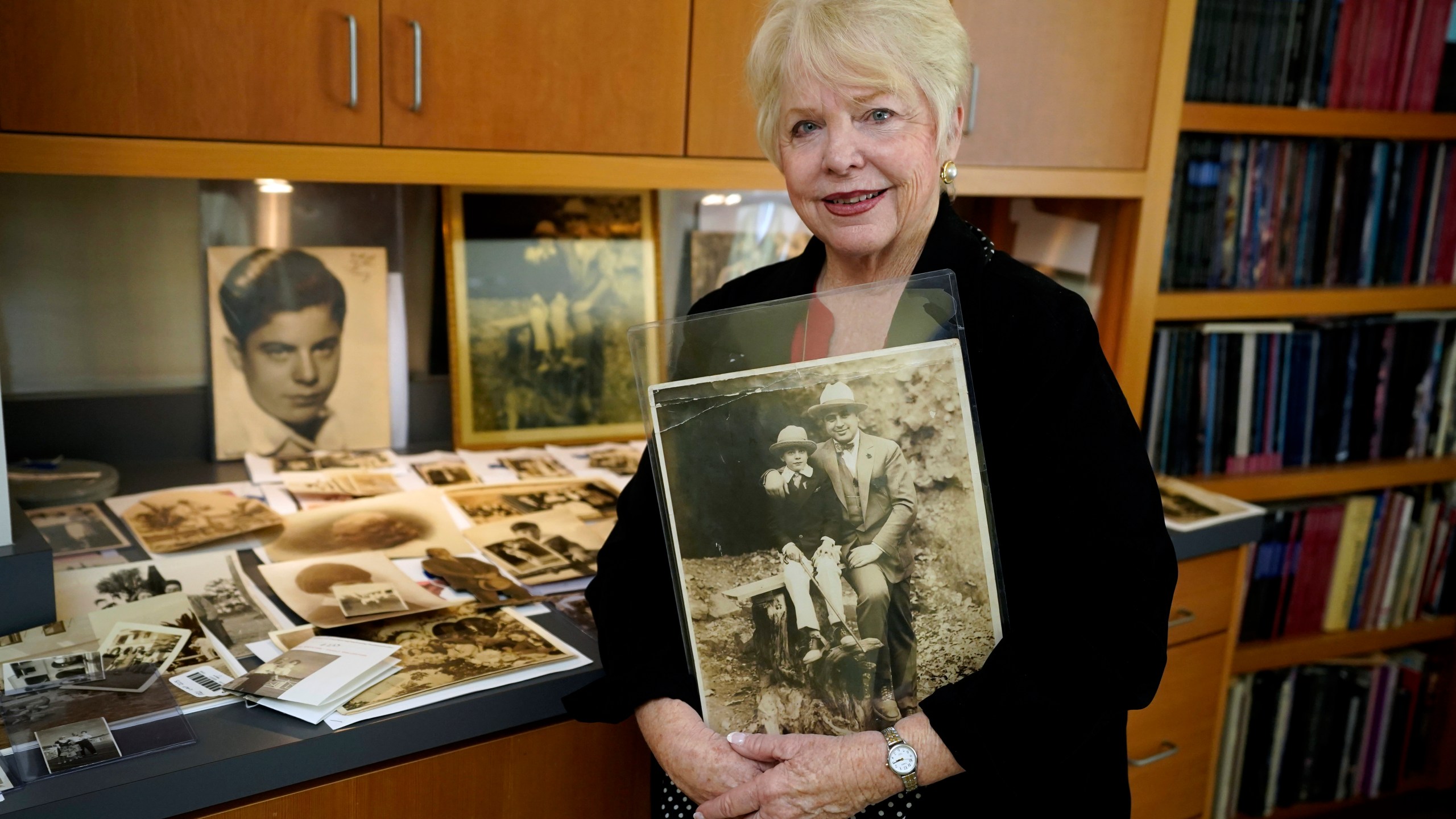 Diane Capone holds a copy of a photograph of her father, Albert "Sonny" Capone as a young boy and her grandfather Al Capone on display at Witherell's Auction House in Sacramento, Calif., Wednesday, Aug. 25, 2021. The granddaughter of the famous mob boss and her two surviving sisters will sell 174 family heirlooms at an Oct. 8 auction titled "A Century of Notoriety: The Estate of Al Capone," that will be held by Witherell's in Sacramento. (AP Photo/Rich Pedroncelli)