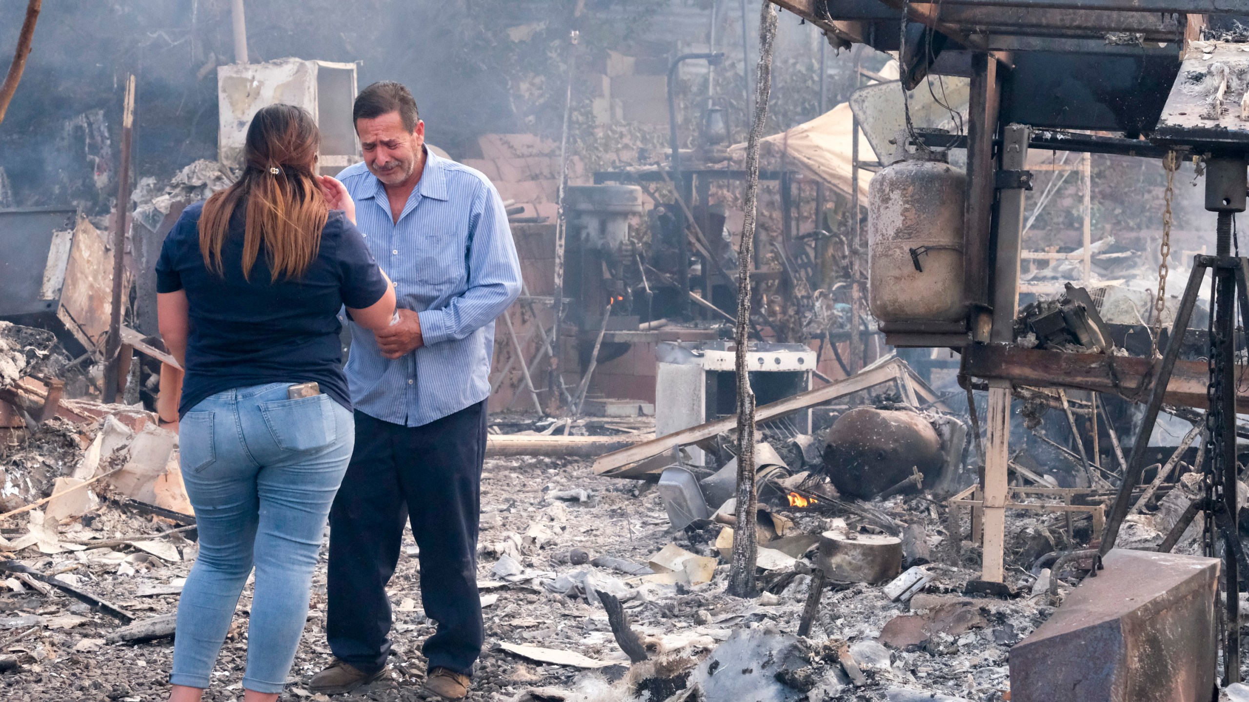 Homeowner Jose Lamas, right, and his daughter Astrid Covarrubias survey the charred debris left in his burned-out home from the South Fire in Lytle Creek, San Bernardino County, north of Rialto, Calif., Wednesday, Aug. 25, 2021. (AP Photo/Ringo H.W. Chiu)