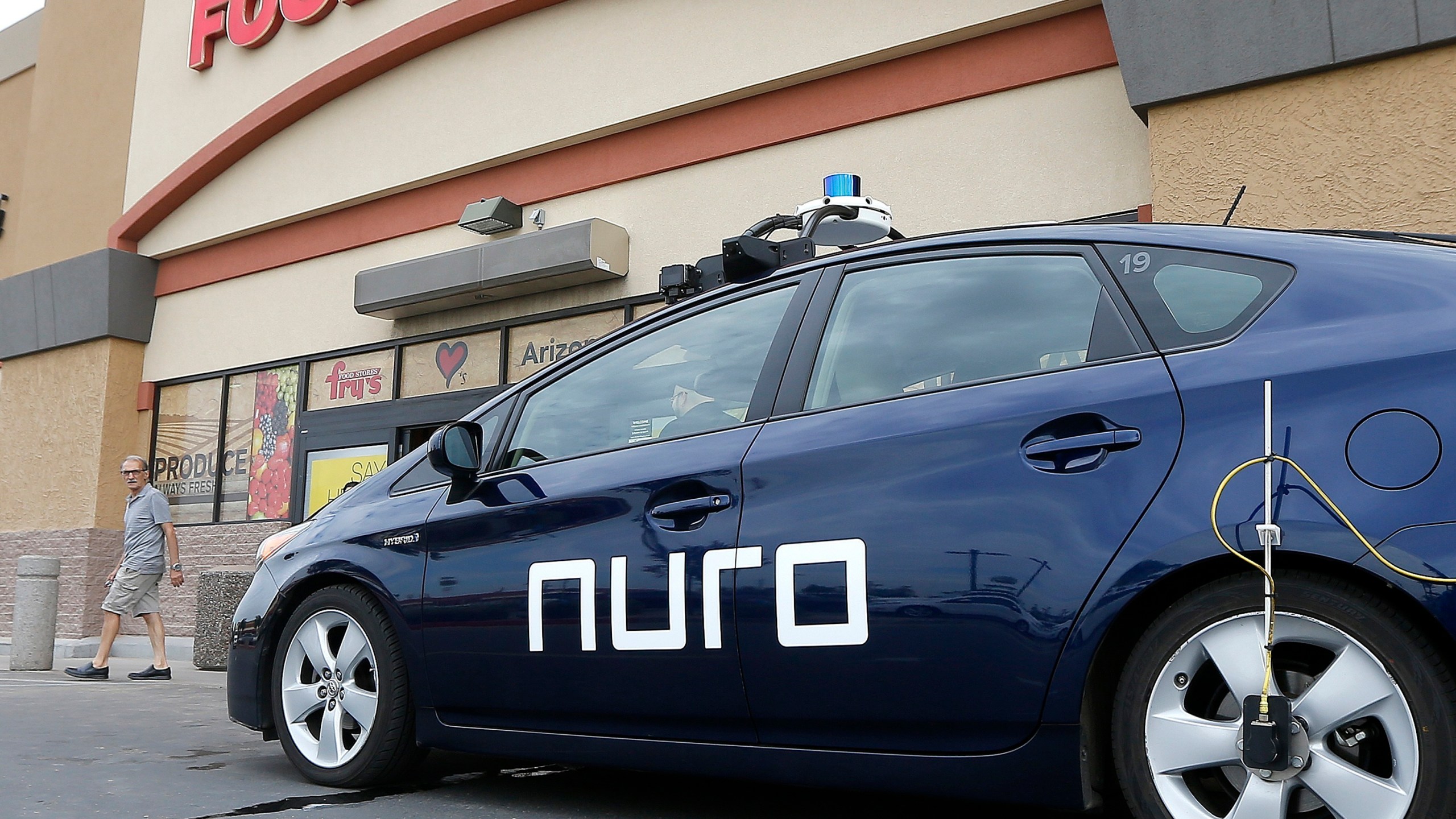 In this Aug. 16, 2018, file photo, a self-driving Nuro vehicle parks outside a Fry's supermarket, which is owned by Kroger, as part of a pilot program for grocery deliveries in Scottsdale, Ariz. Nuro, the robotics company that develops driverless vehicles for on-road grocery, pizza and prescription deliveries said Thursday, Aug. 26, 2021, it intends to spend $40 million to put a manufacturing facility at the Las Vegas Motor Speedway. (AP Photo/Ross D. Franklin, File)