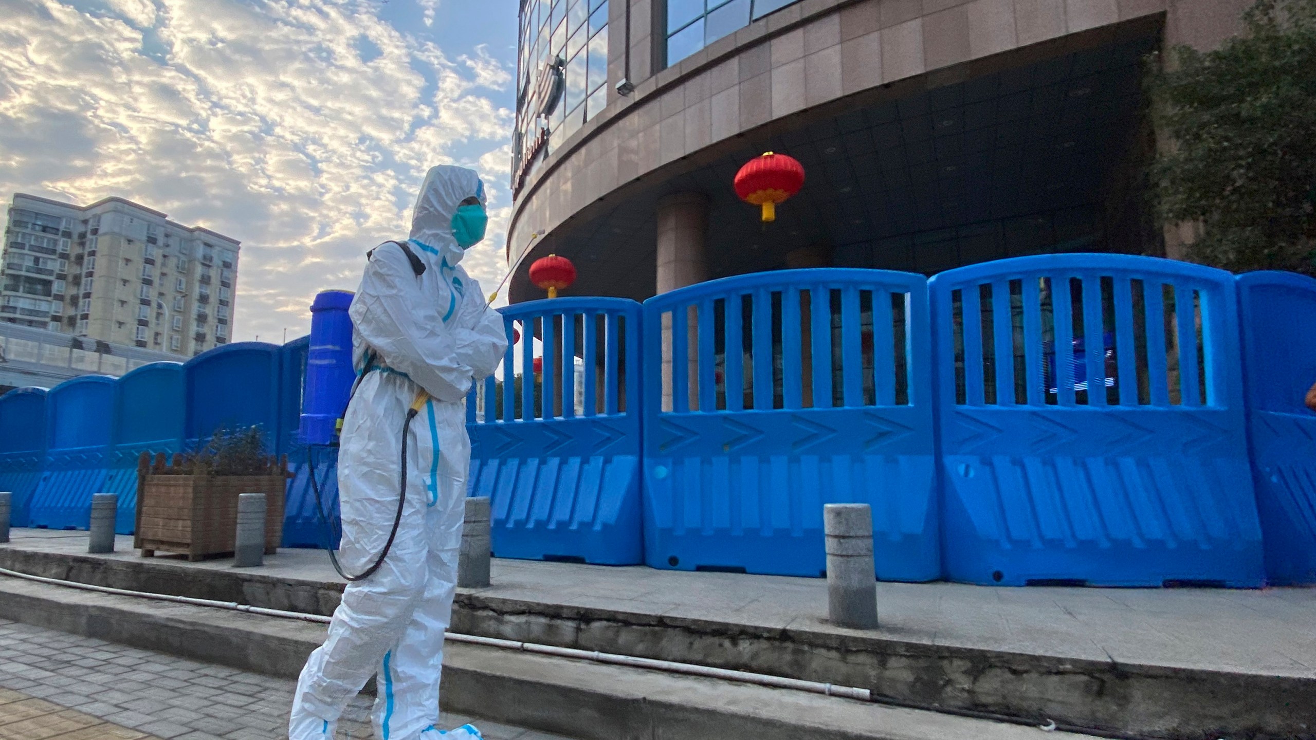 In this Feb. 6, 2021, file a worker in protectively overalls and carrying disinfecting equipment walks outside the Wuhan Central Hospital where Li Wenliang, the whistleblower doctor who sounded the alarm and was reprimanded by local police for it in the early days of Wuhan's pandemic, worked in Wuhan in central China. U.S. intelligence agencies remain divided on the origins of the coronavirus but believe China's leaders did not know about the virus before the start of the global pandemic, according to results released Friday, Aug. 27, of a review ordered by President Joe Biden. (AP Photo/Ng Han Guan, File)