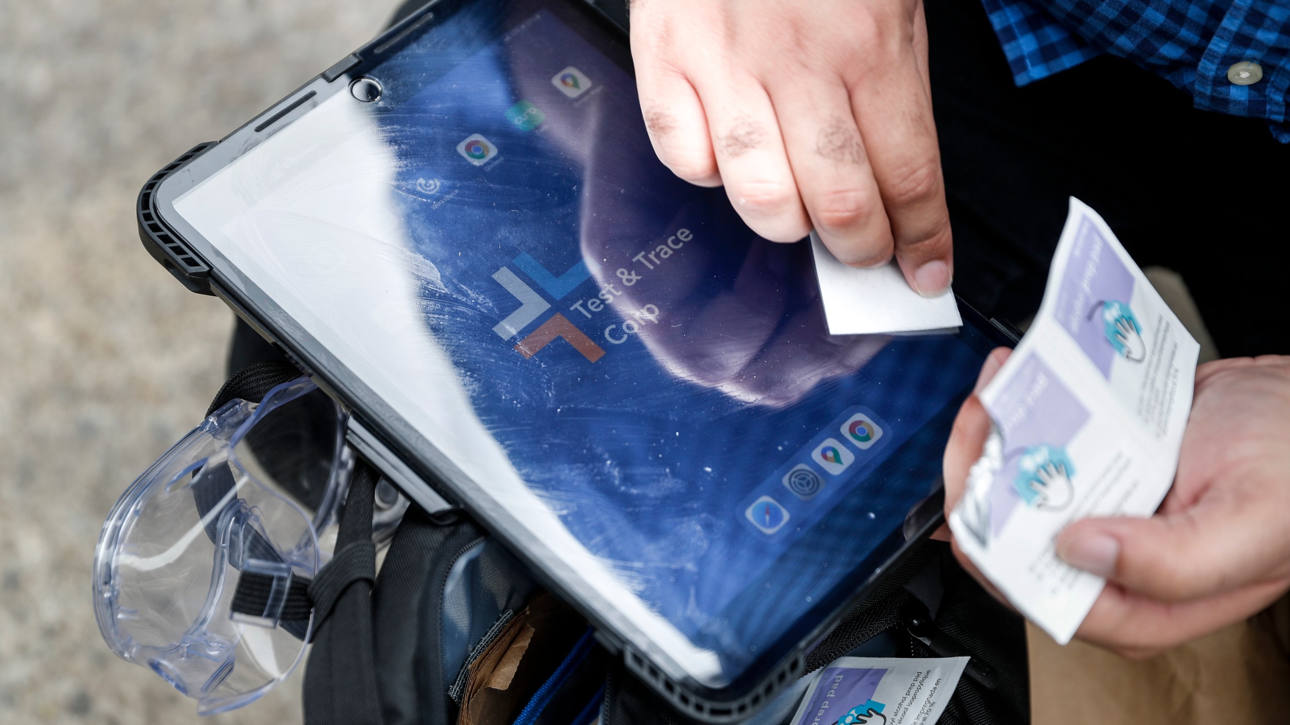 In this Aug. 6, 2020 file photo, Joseph Ortiz, a contact tracer with New York City's Health + Hospitals battling the coronavirus pandemic, disinfects his tablet after leaving a potential patient's home in New York. (AP Photo/John Minchillo, File)