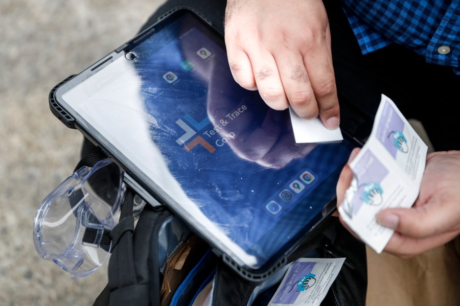 In this Aug. 6, 2020 file photo, Joseph Ortiz, a contact tracer with New York City's Health + Hospitals battling the coronavirus pandemic, disinfects his tablet after leaving a potential patient's home in New York. (AP Photo/John Minchillo, File)