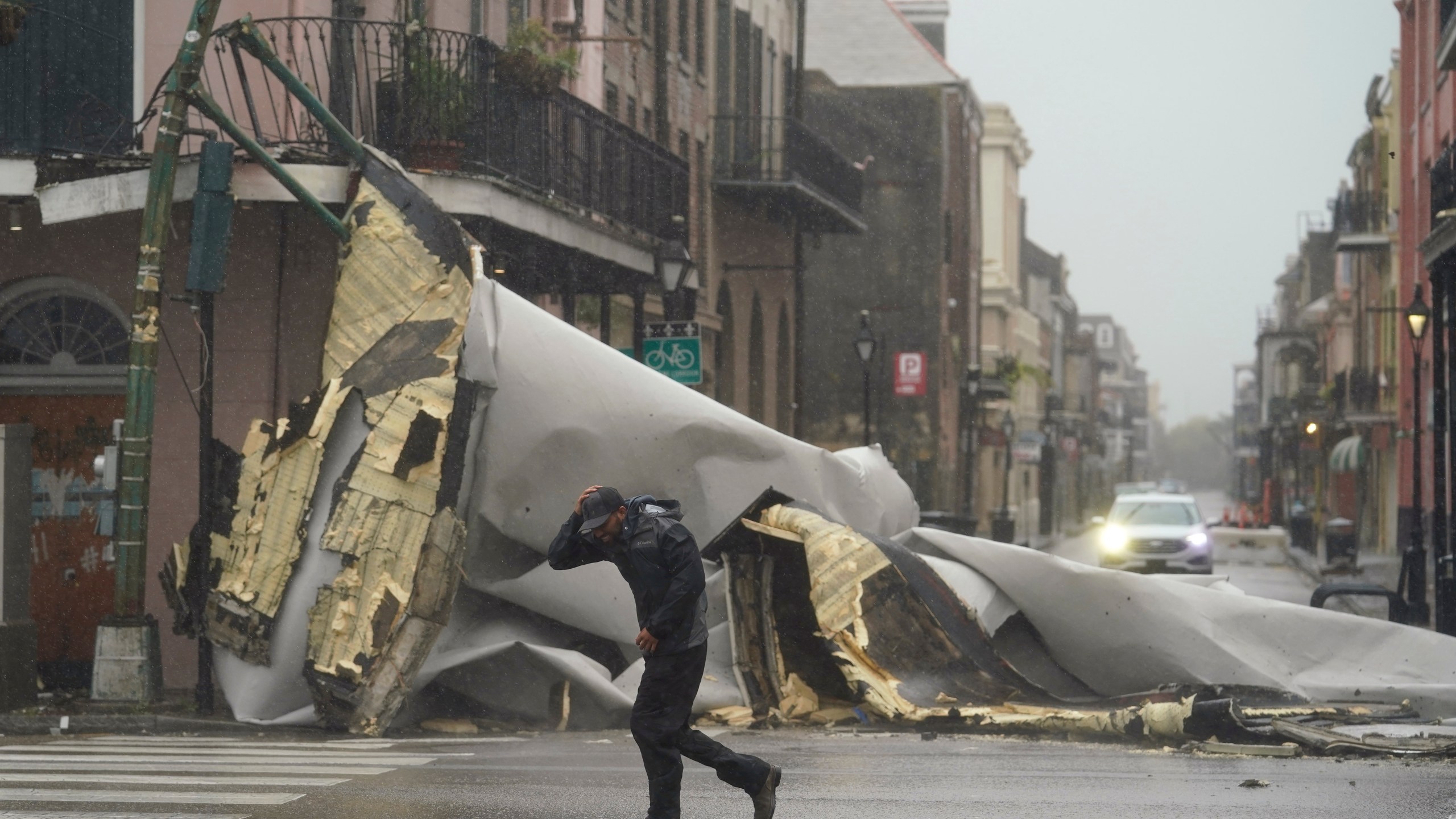 A man passes by a section of roof that was blown off of a building in the French Quarter by Hurricane Ida winds, Sunday, Aug. 29, 2021, in New Orleans. (AP Photo/Eric Gay)