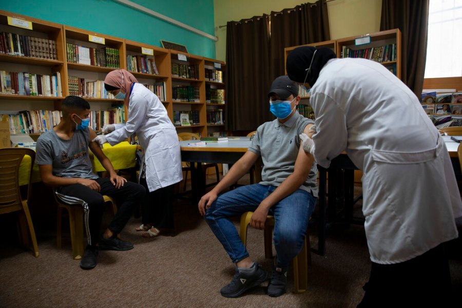 Health workers administer Moderna COVID-19 vaccines to Palestinian students during a back to school vaccination campaign, in the West Bank city of Ramallah, Monday, Aug. 30, 2021. (AP Photo/Majdi Mohammed)